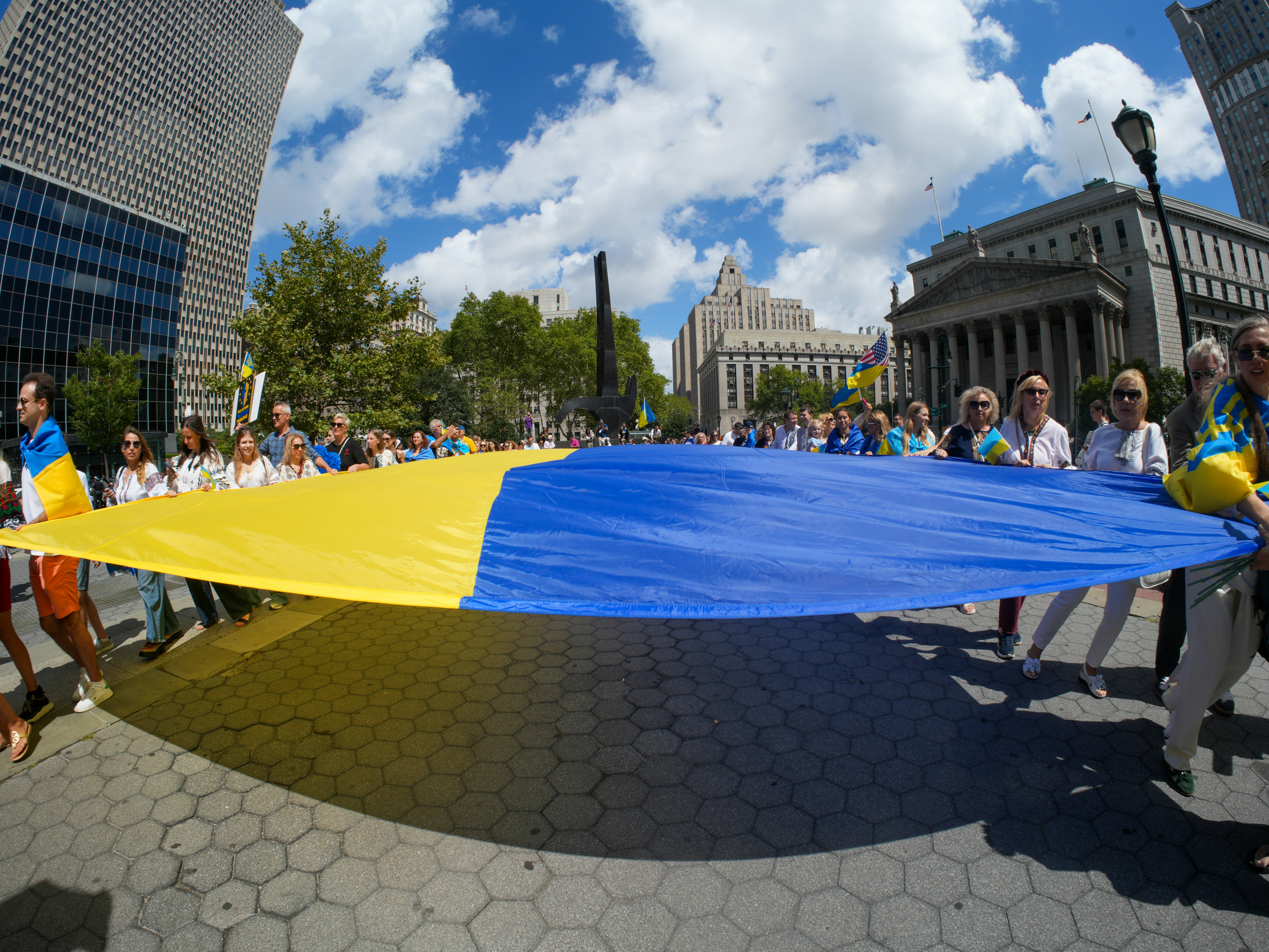 People holding a large ukrainian flag during a parade.
