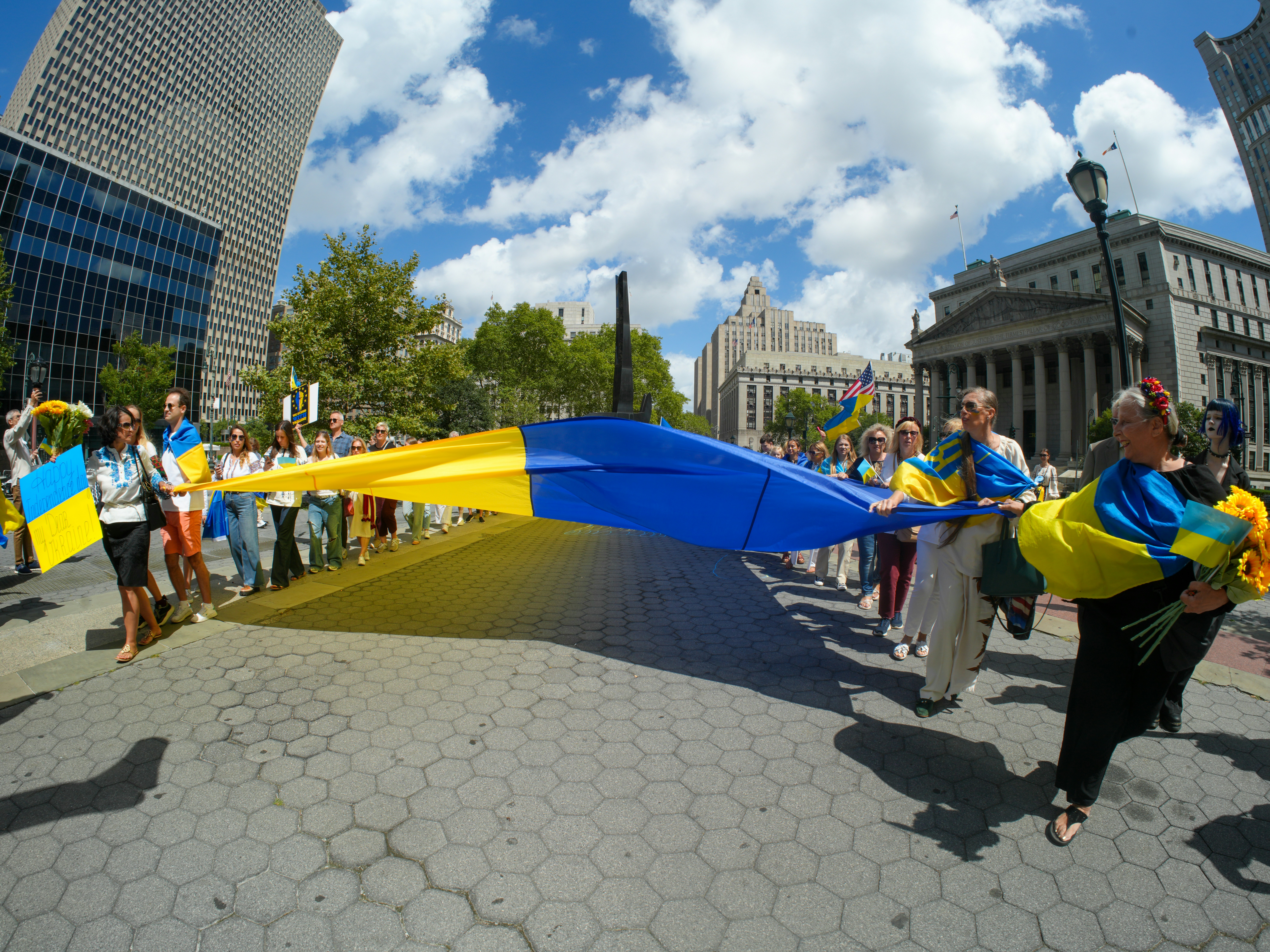 People carry a large ukrainian flag in a city street