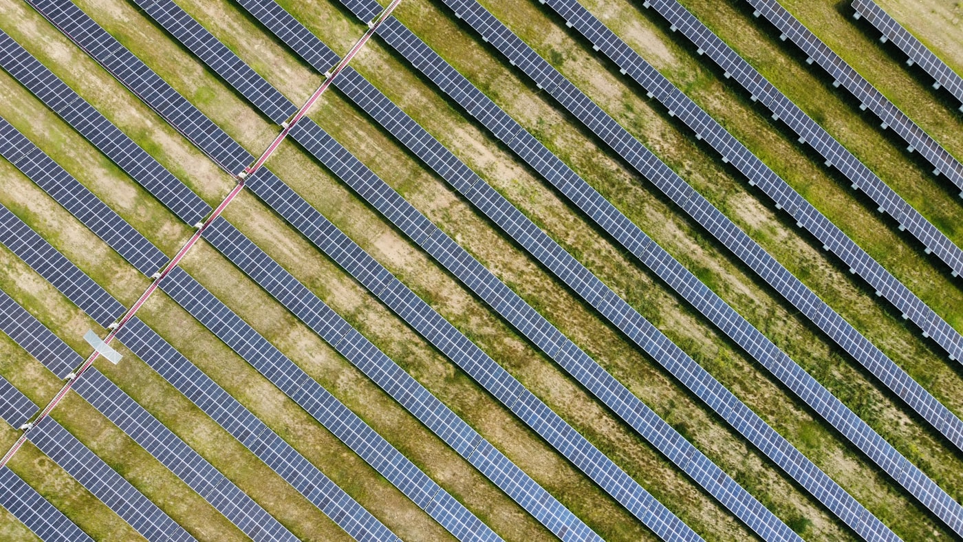 Aerial view of solar panels across a grassy field