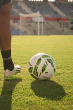 Soccer ball on a grassy field with player's foot.