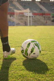 Soccer ball on a grassy field with player's foot.
