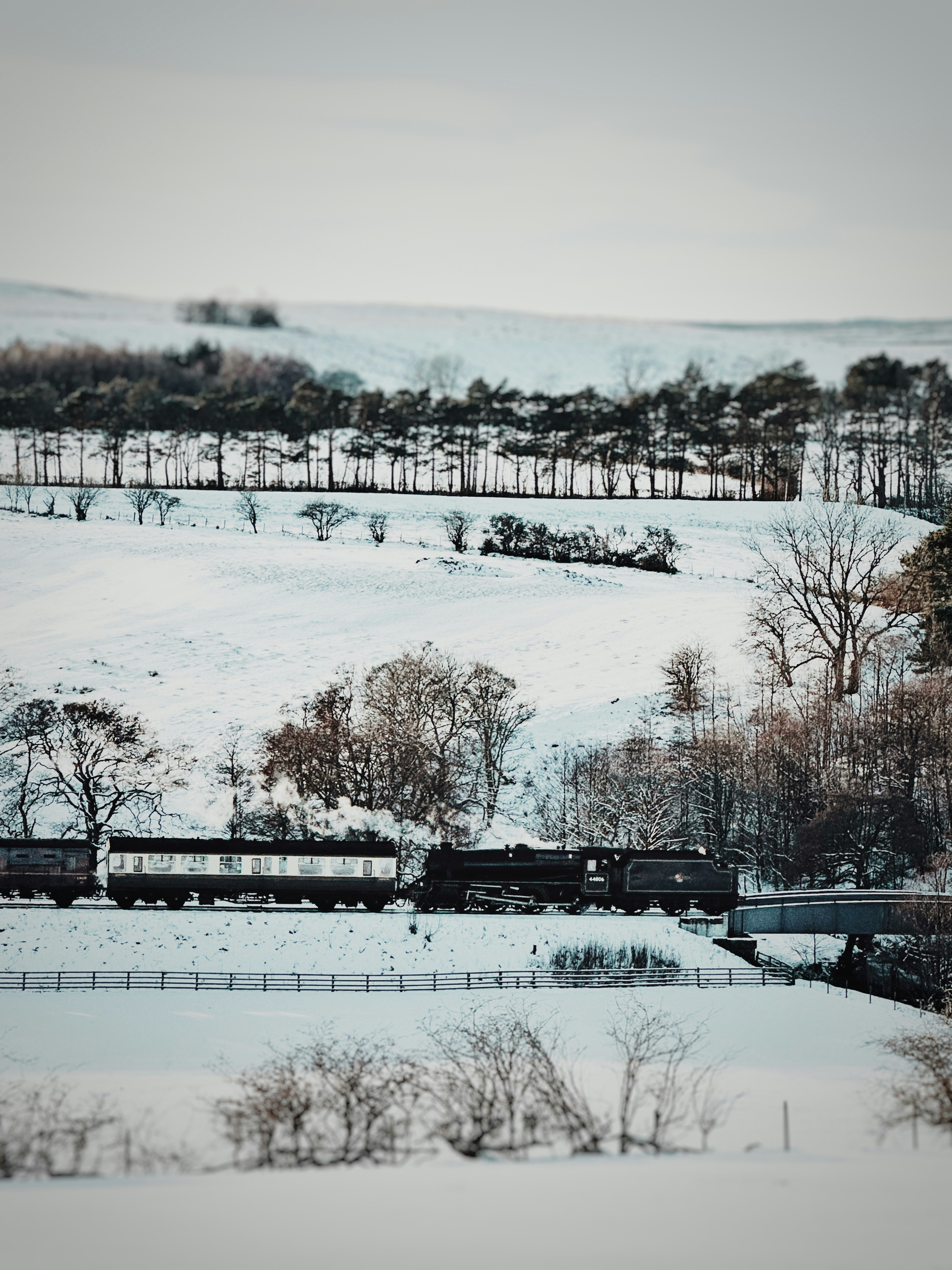 A steam train travels through a snowy landscape.
