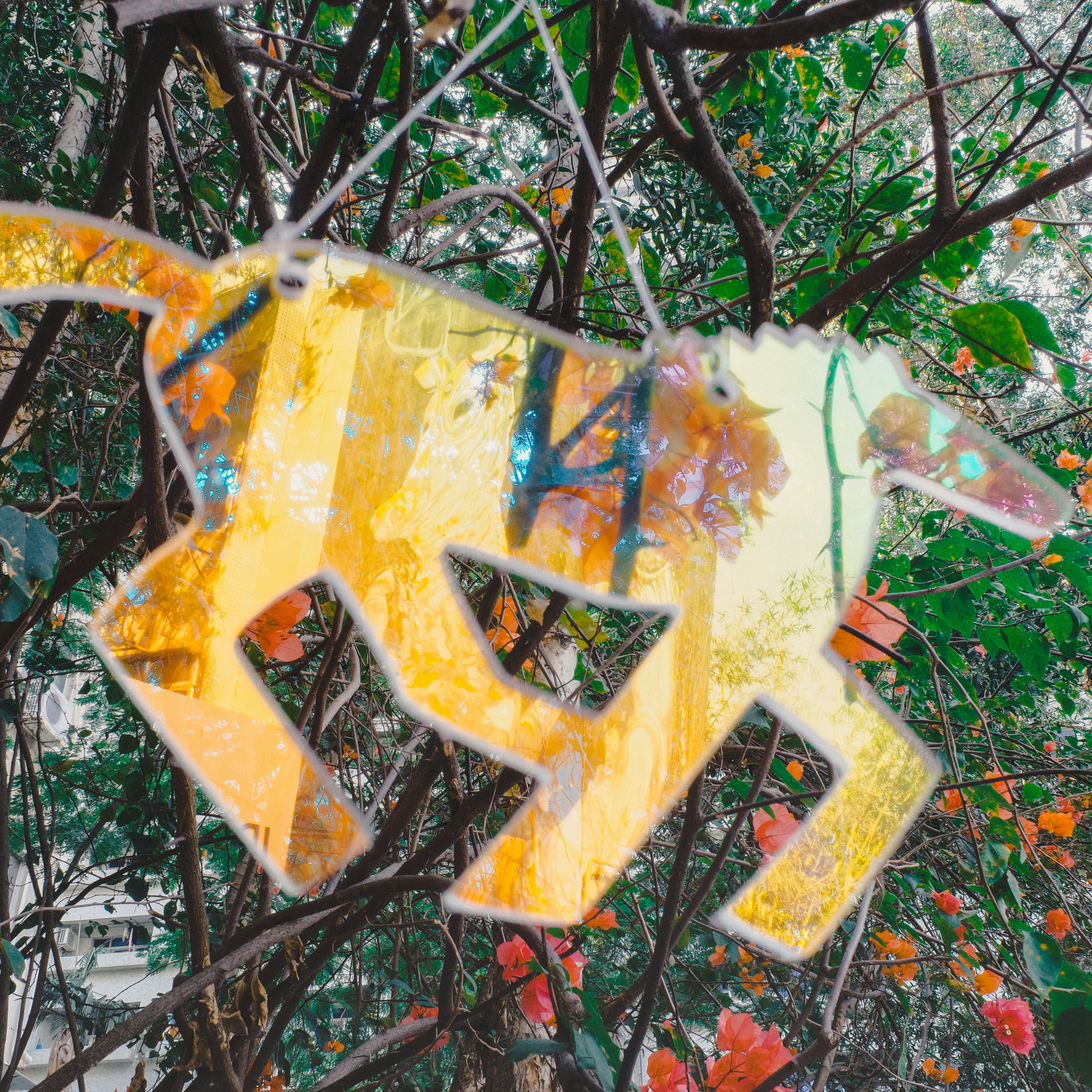 Une découpe décorative jaune est suspendue parmi les branches et les fleurs.