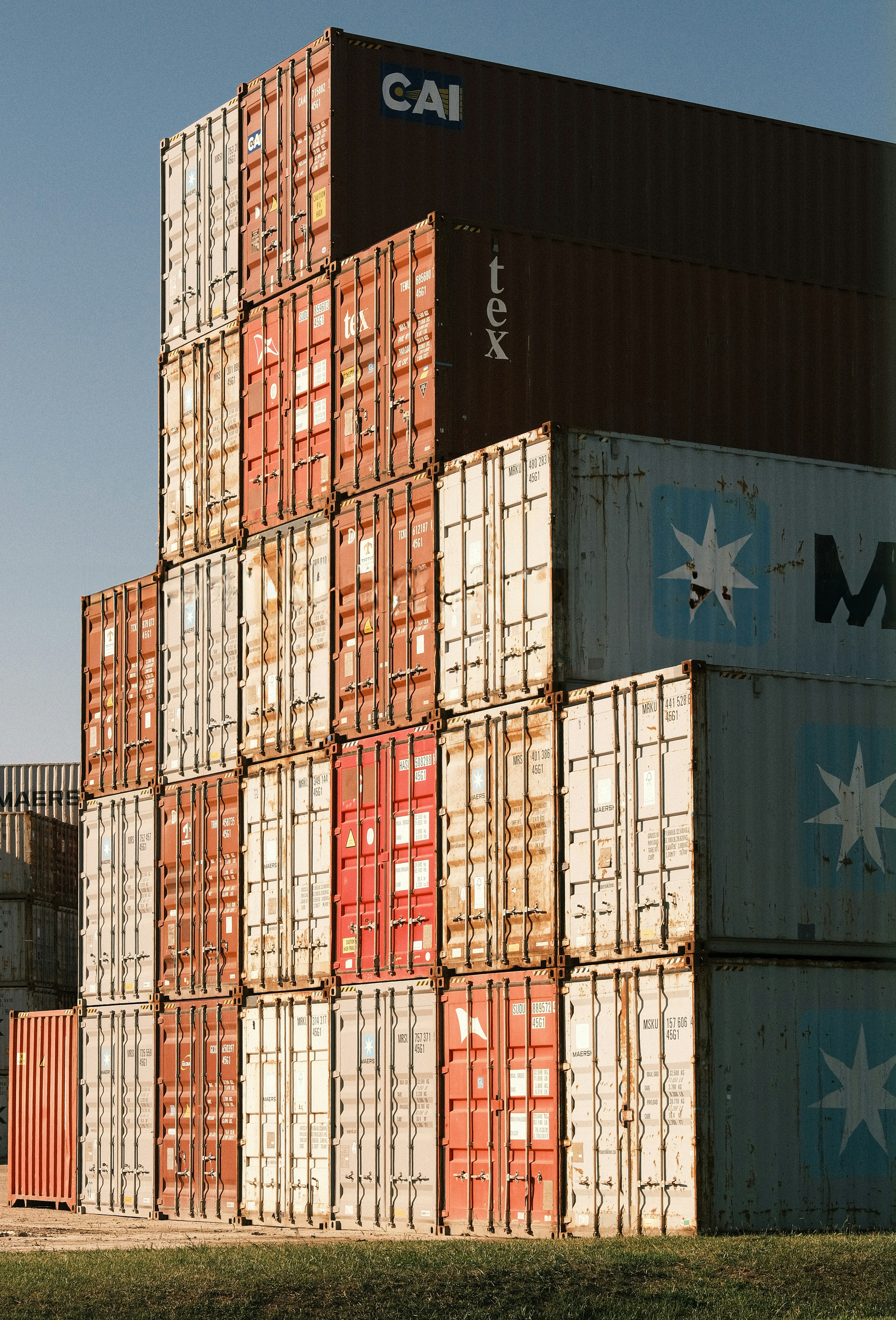 Stack of colorful shipping containers against a clear blue sky.