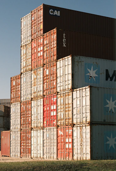 Stack of colorful shipping containers against a clear blue sky.