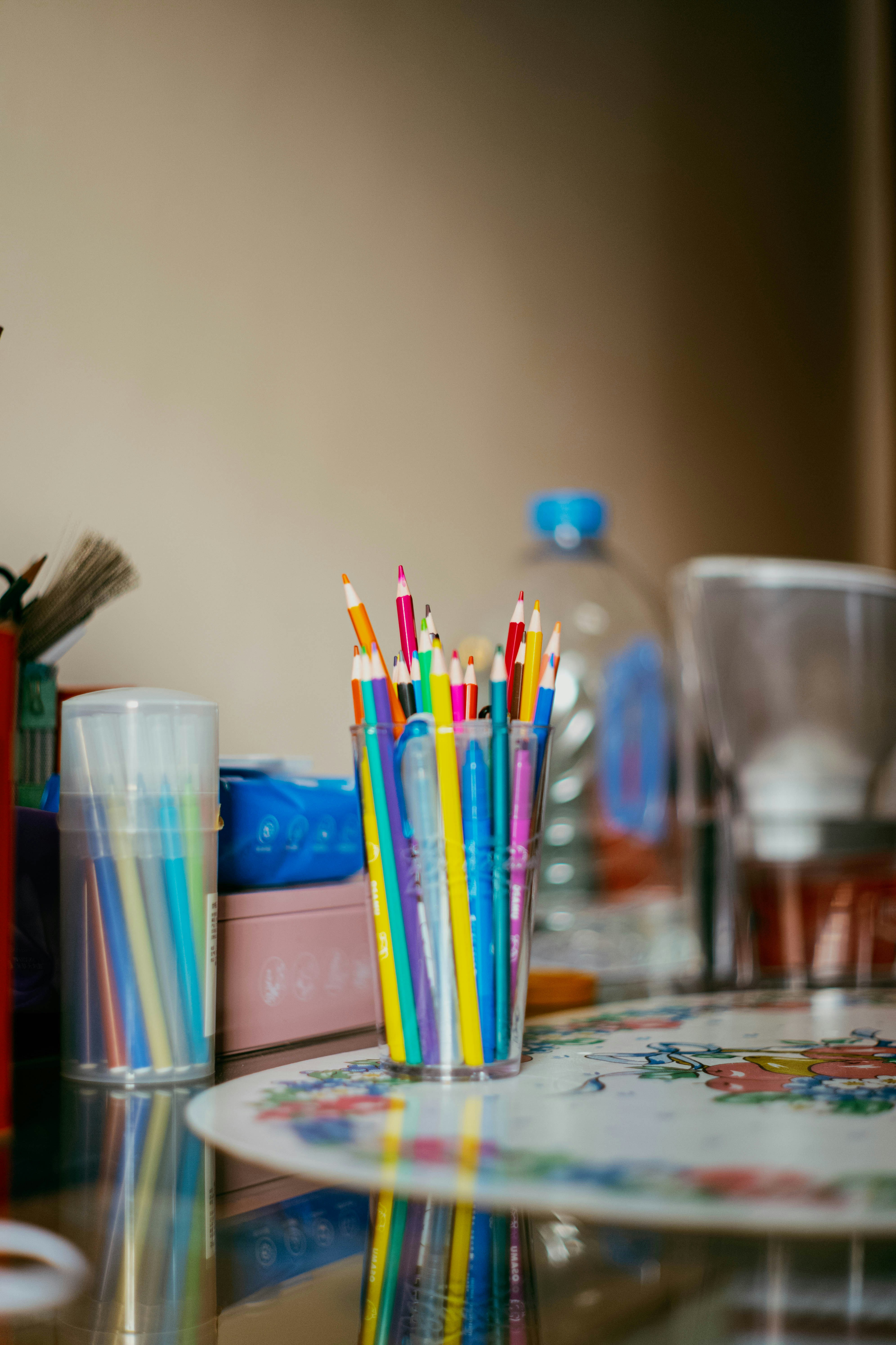 Colored pencils in a clear cup on a table.