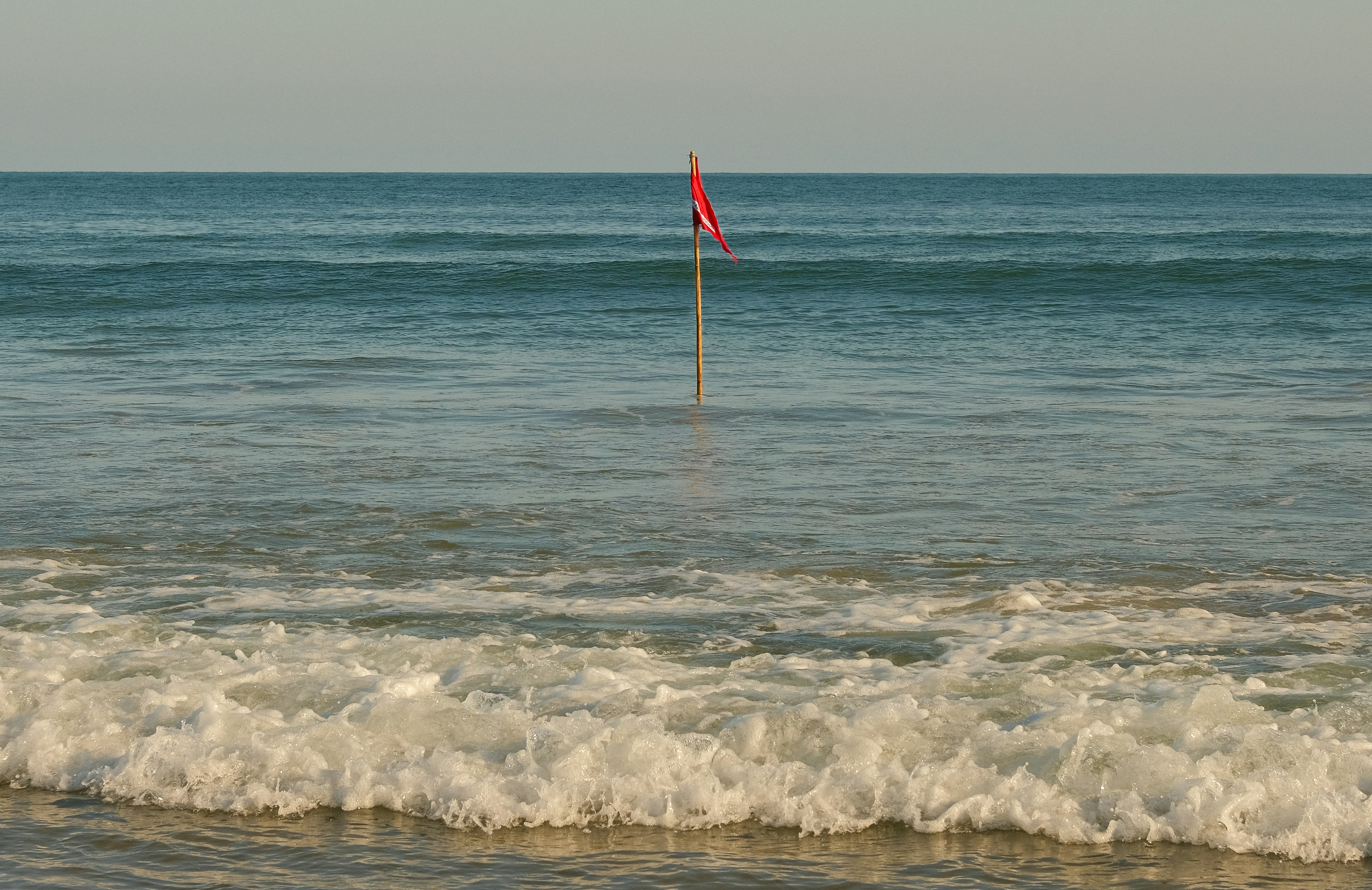 Red flag on a pole in the ocean