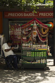 Man sitting by a colorful street vendor cart
