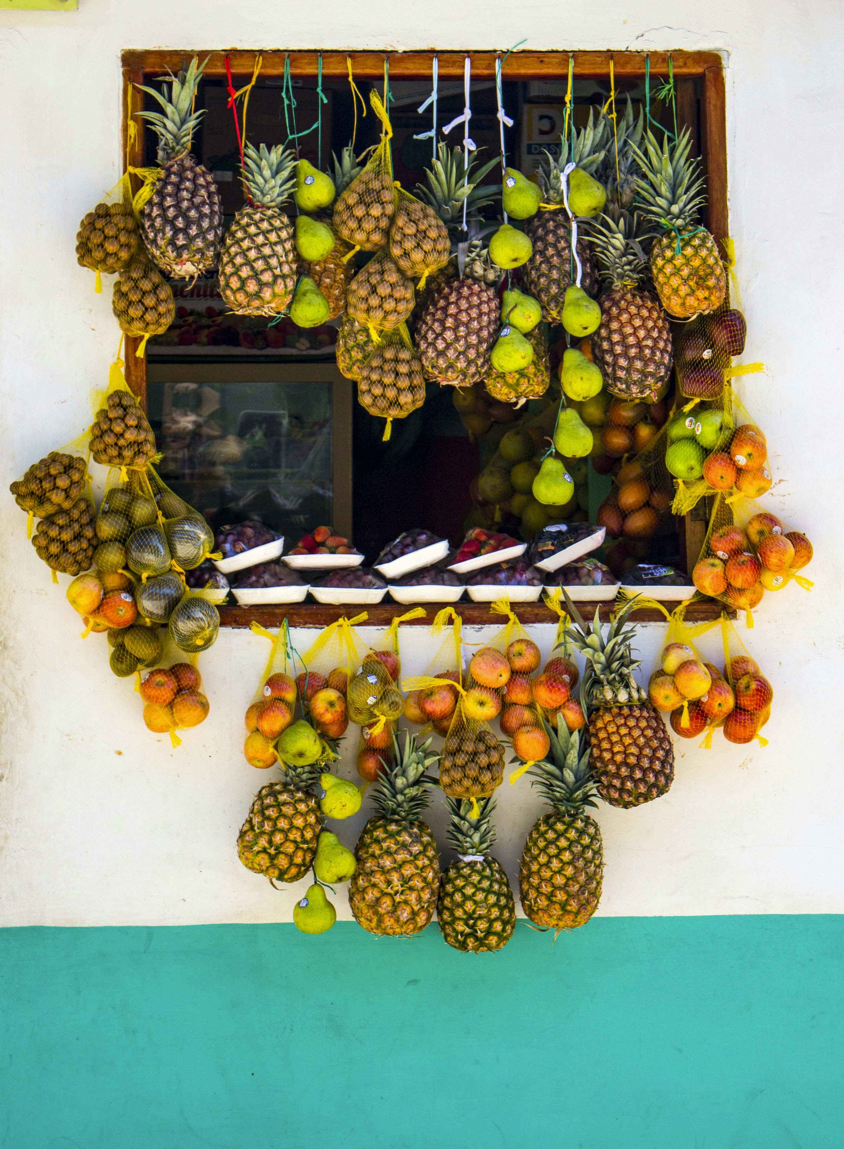 Fresh fruits hanging outside a window for sale.