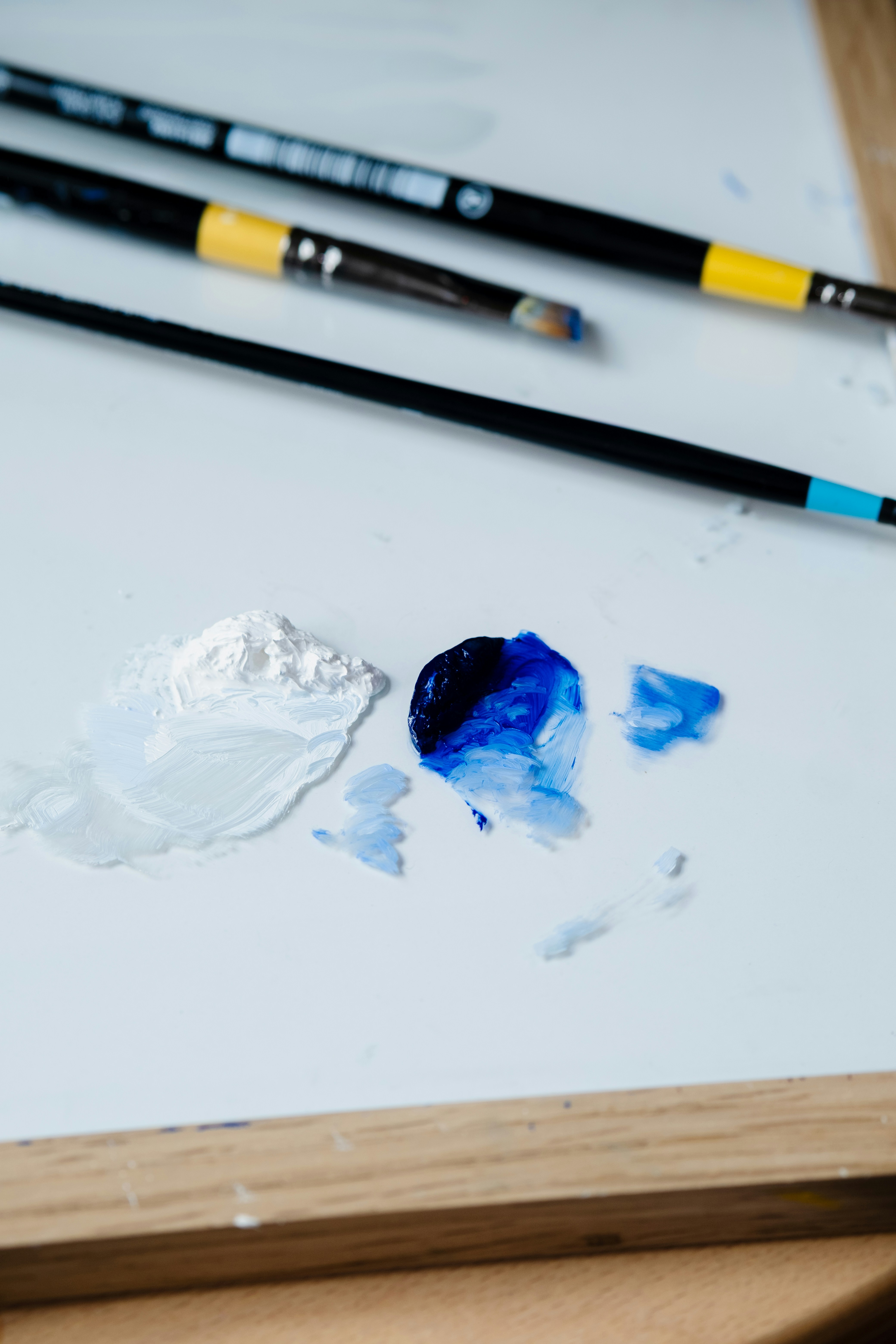 Paintbrushes and paint blobs on a white palette.