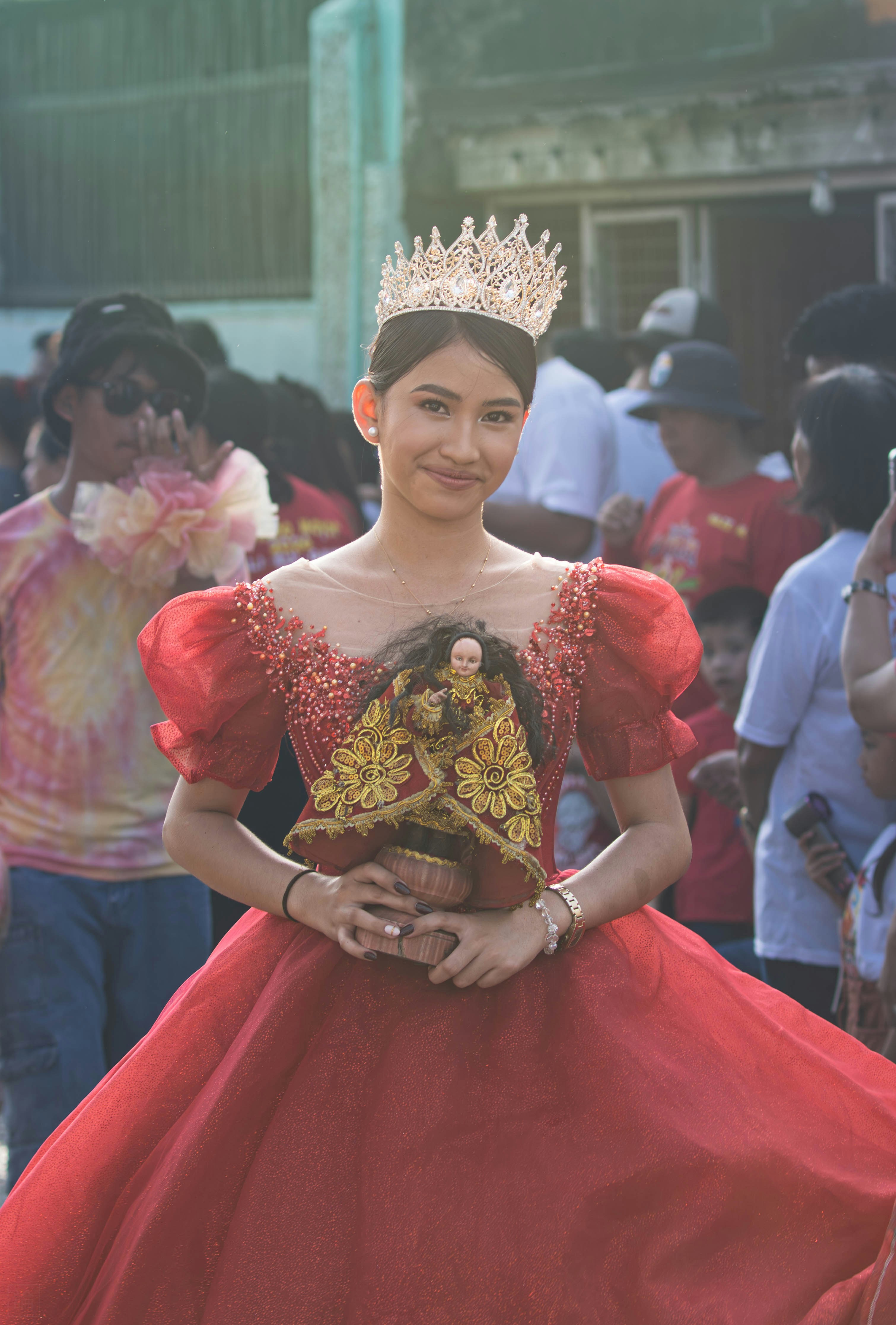 Frau im roten Gewand mit Krone hält eine religiöse Statue.