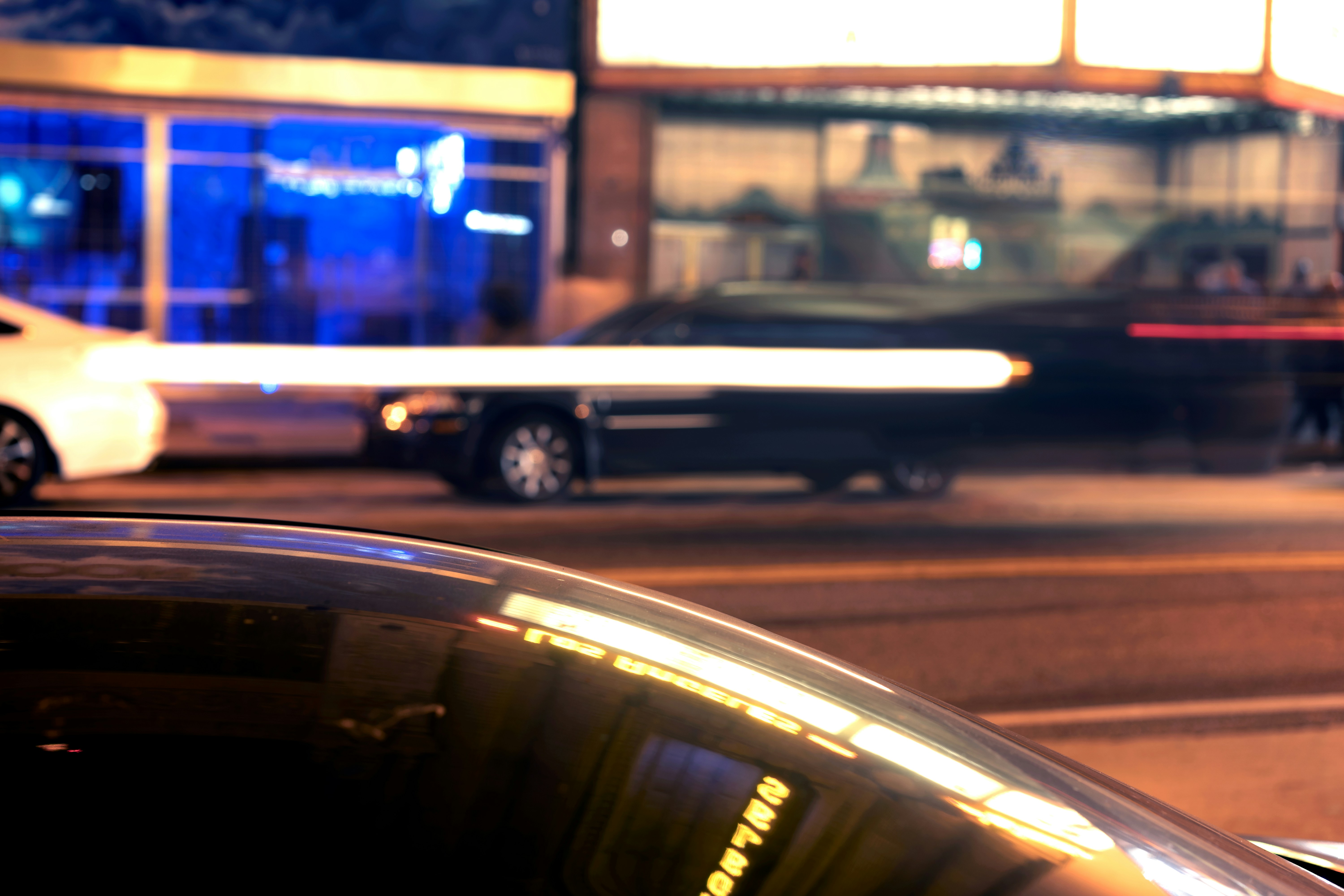 Cars on a city street at night with neon lights.