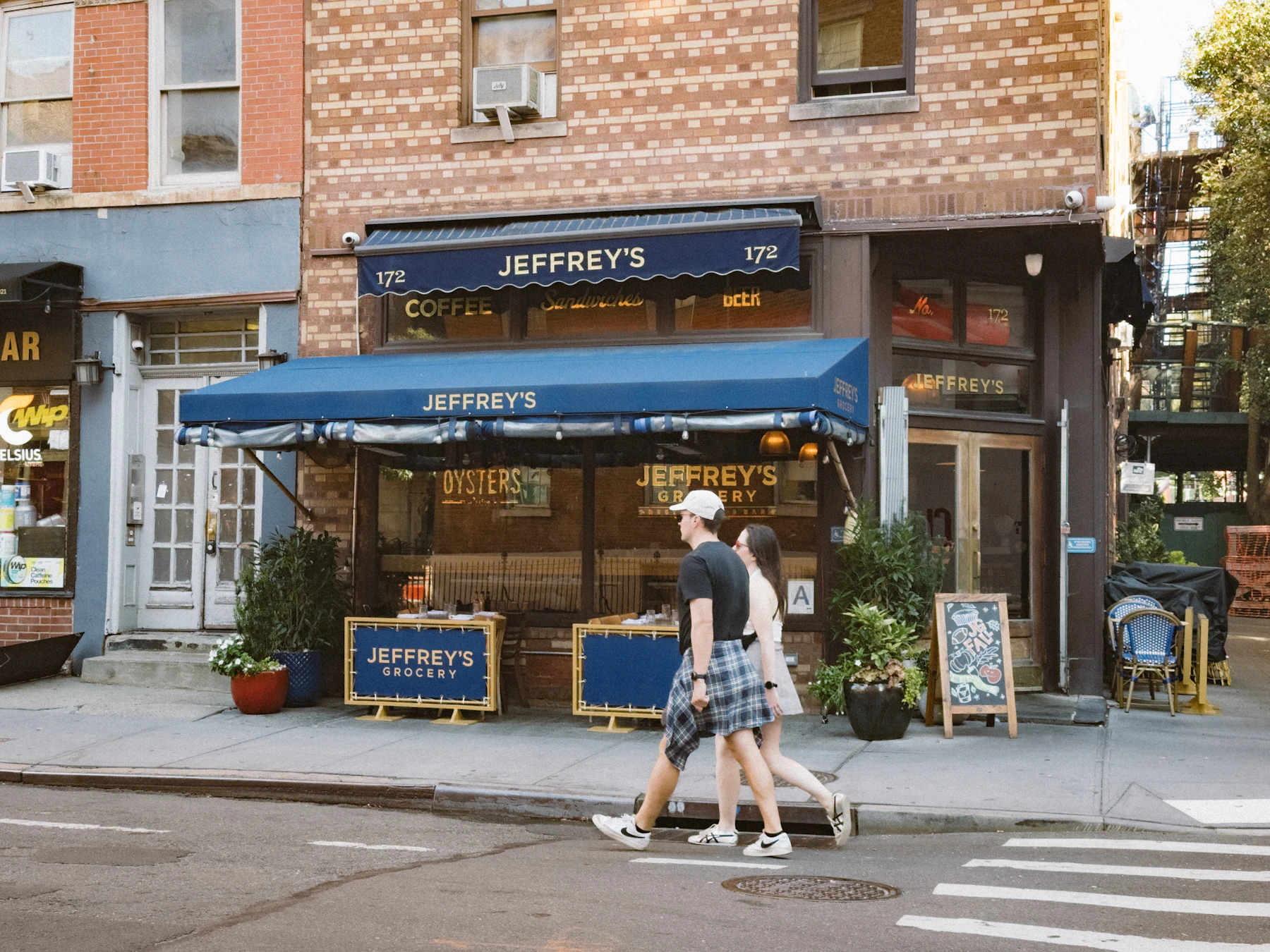 People walking past a grocery storefront on a New York street