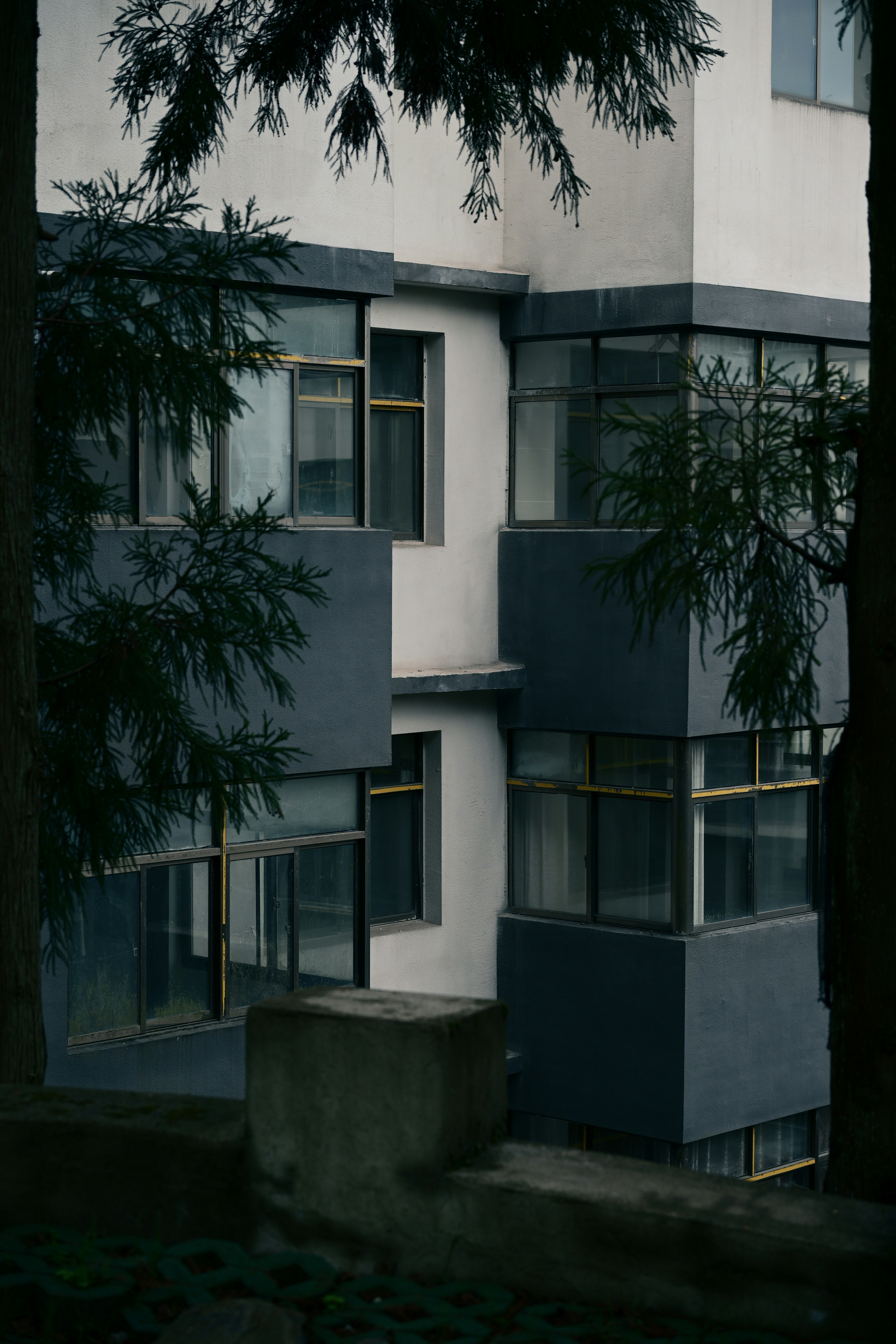 Modern apartment building with dark grey accents and trees.