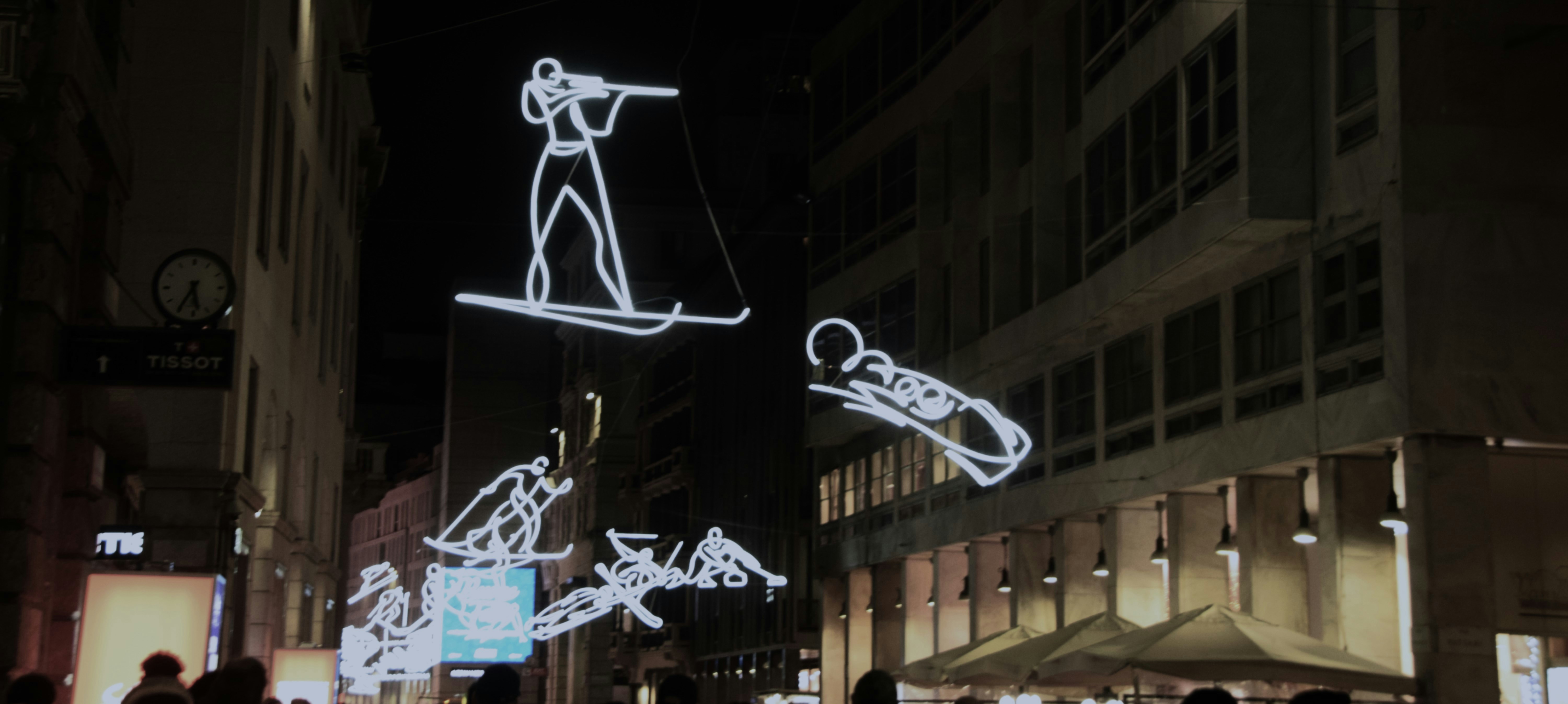 Neon winter sport figures light up city street at night