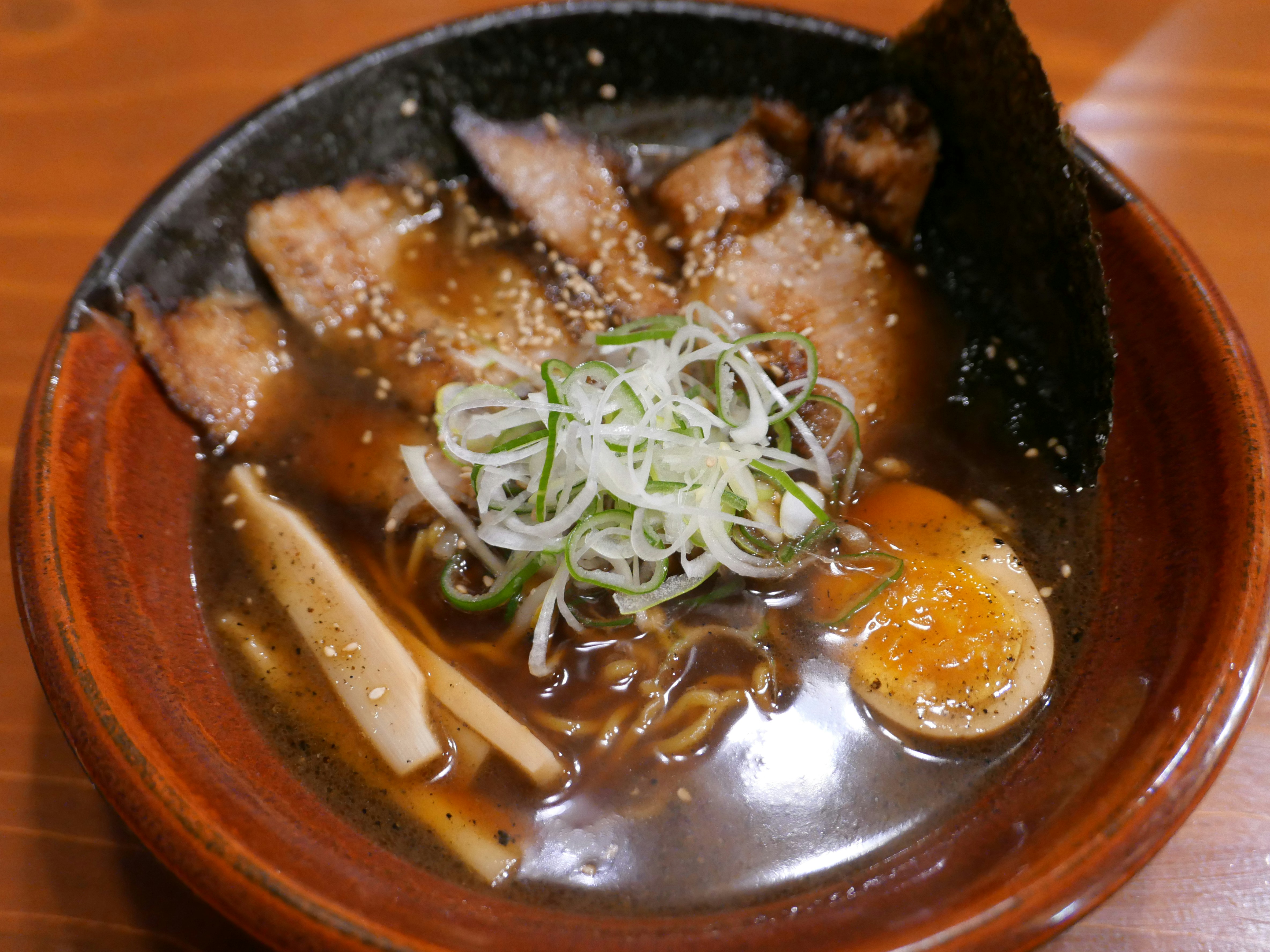 A bowl of ramen with pork, egg, and seaweed