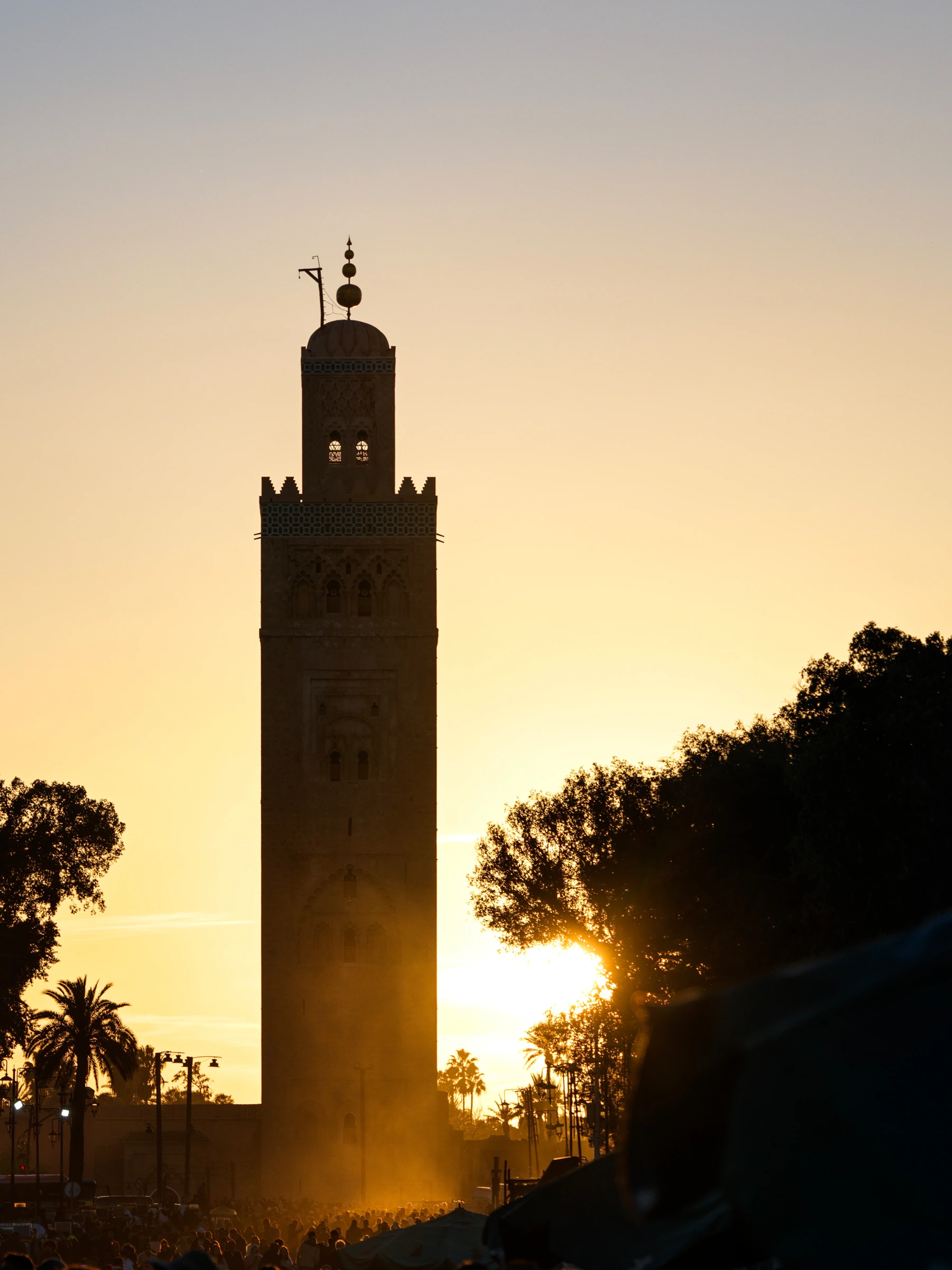 Koutoubia minaret silhouetted above Jemaa el-Fnaa at a warm Marrakech sunset
