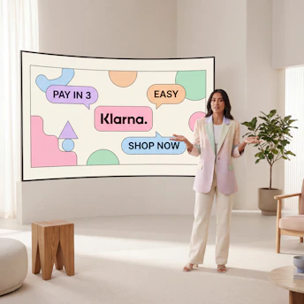 Woman presenting klarna payment options on a large screen.