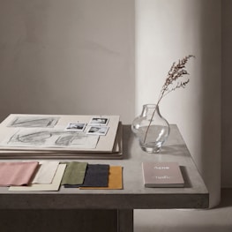 Fabric swatches, sketches, and vase on a table.