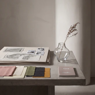 Fabric swatches, sketches, and vase on a table.