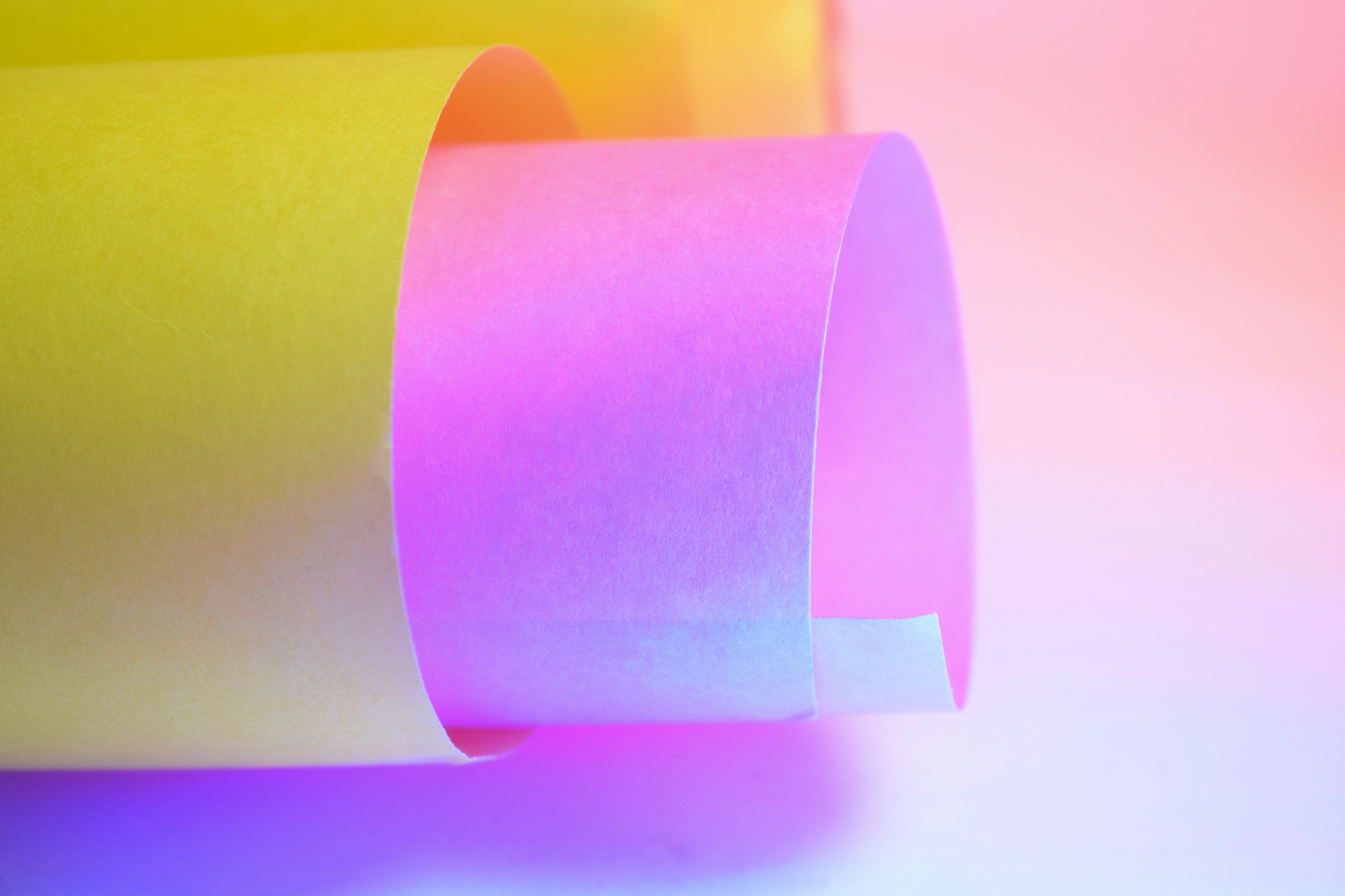 Rolled yellow and pink paper with colorful lighting