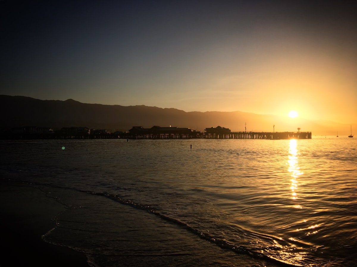 Sunset over a calm ocean with a pier