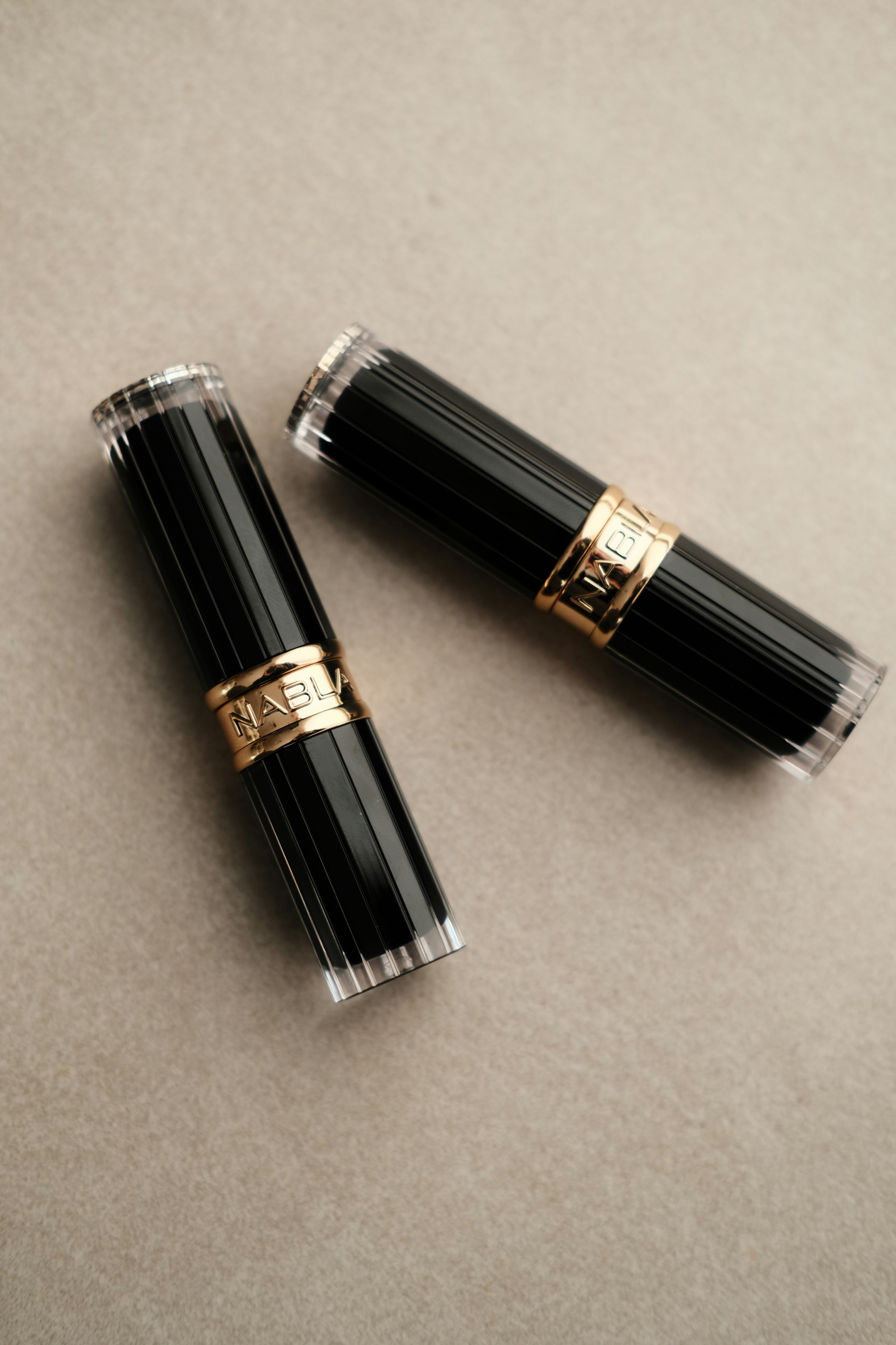 Two black lipstick tubes with gold bands