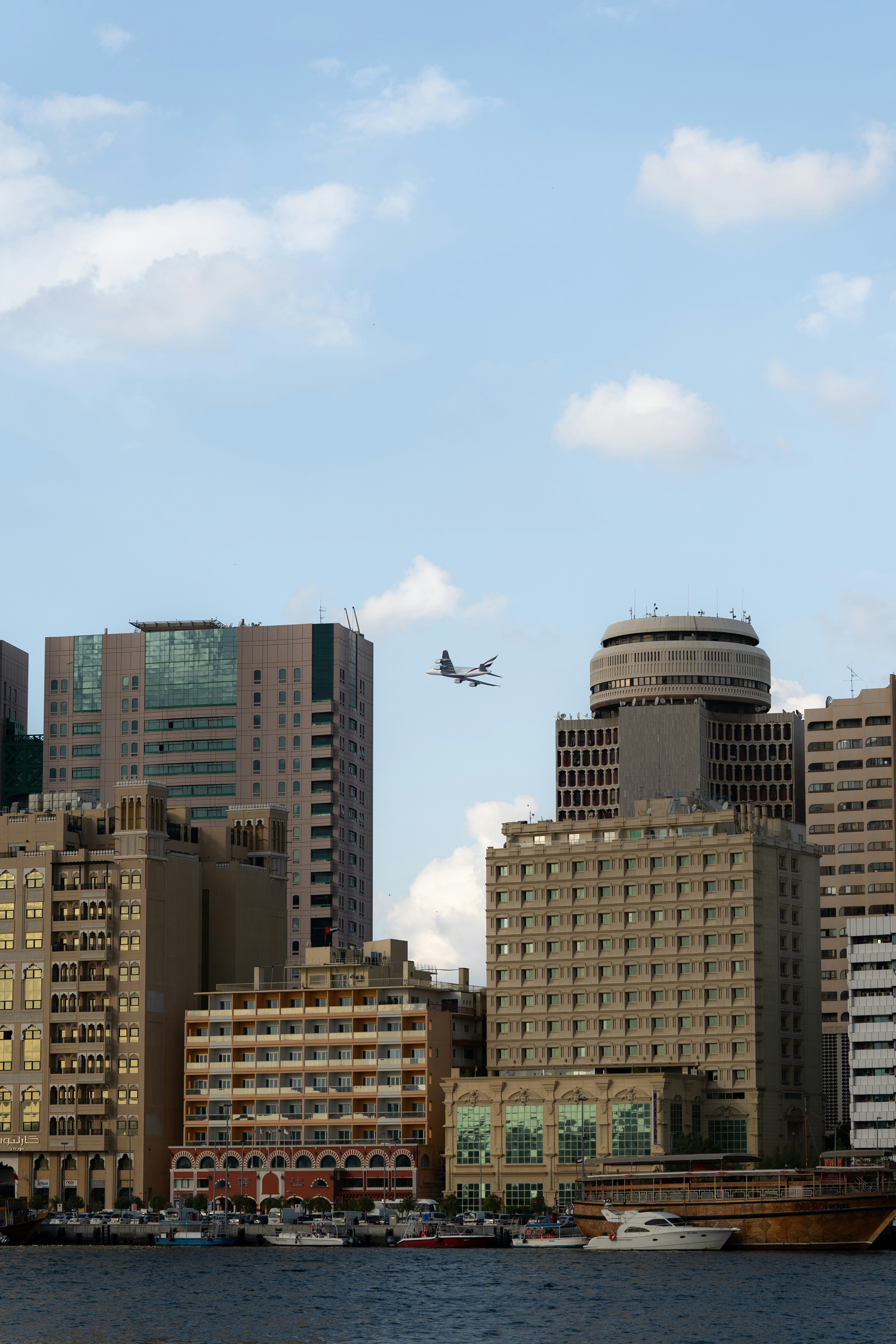 Airplane flying over city buildings and harbor.