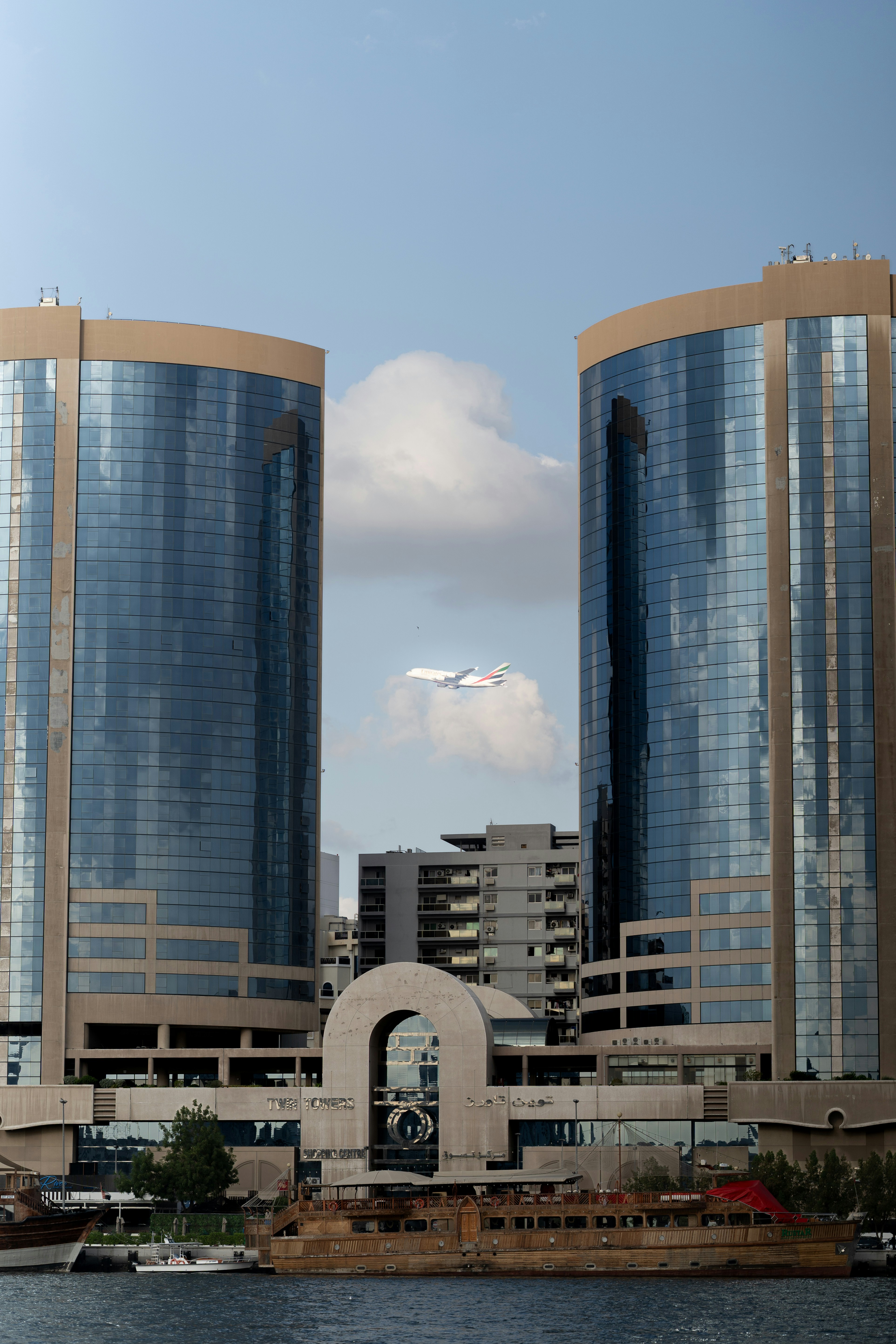 Two modern buildings with an airplane flying between them.