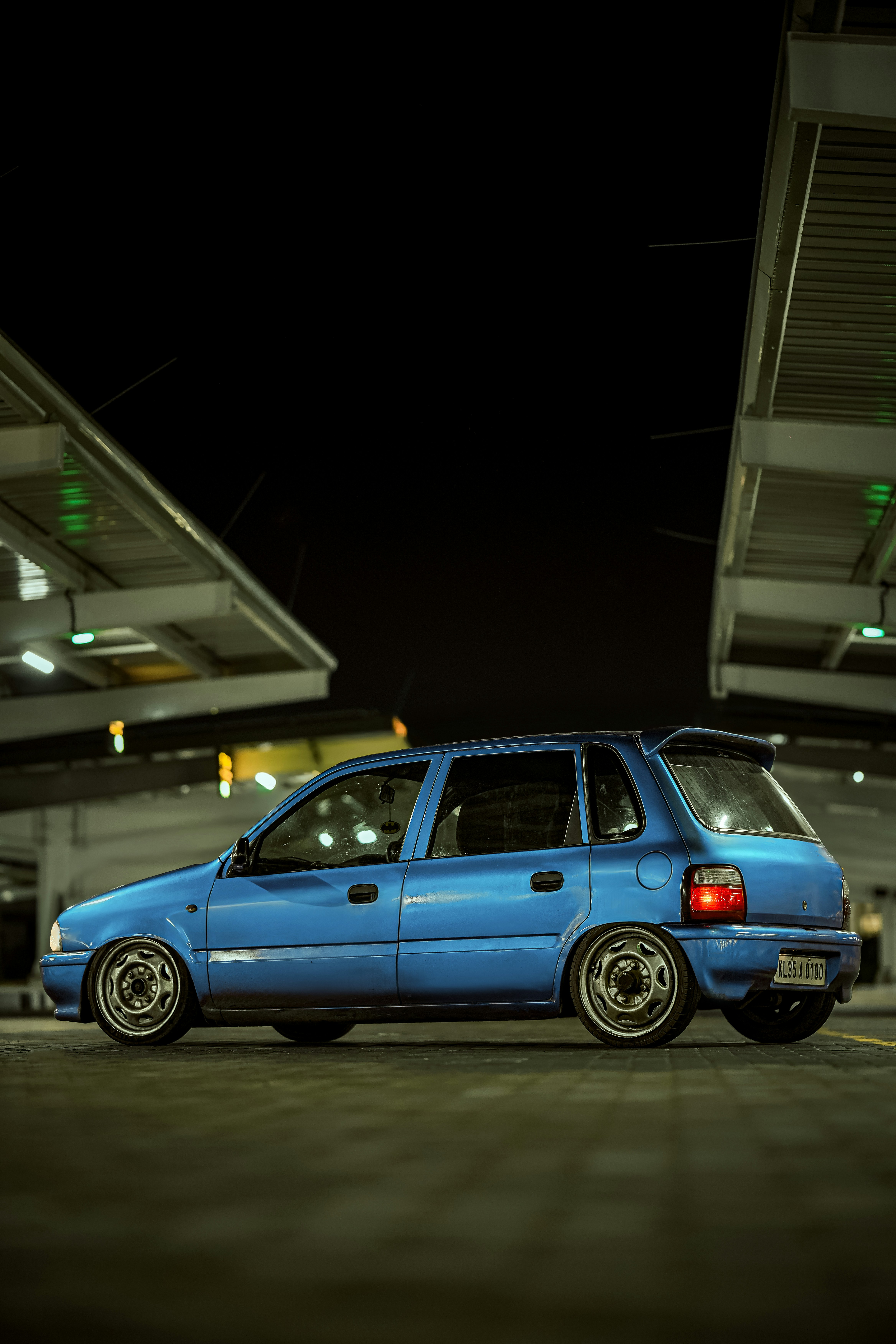A blue car parked under a modern structure at night