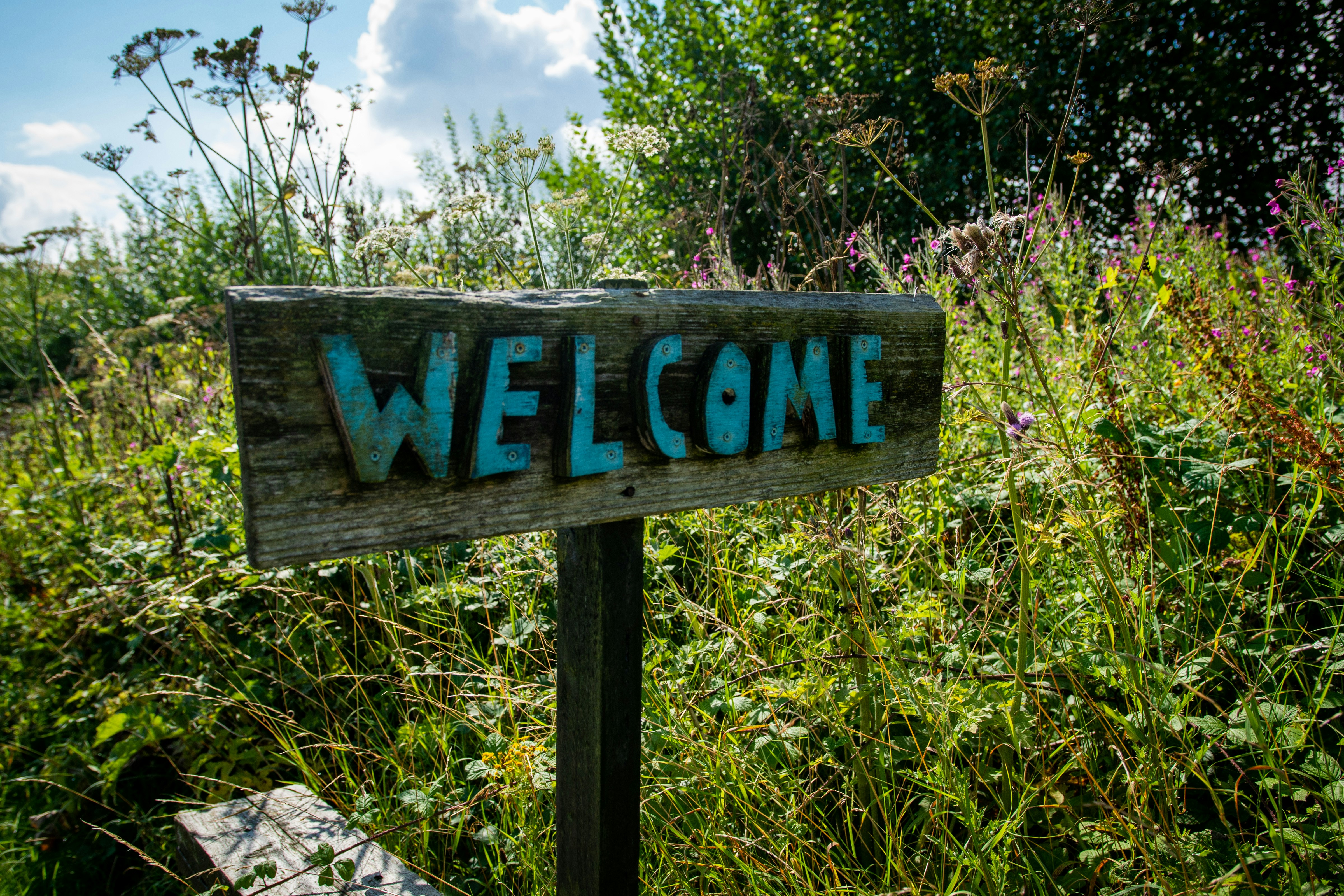 Wooden sign with welcome painted in blue letters.