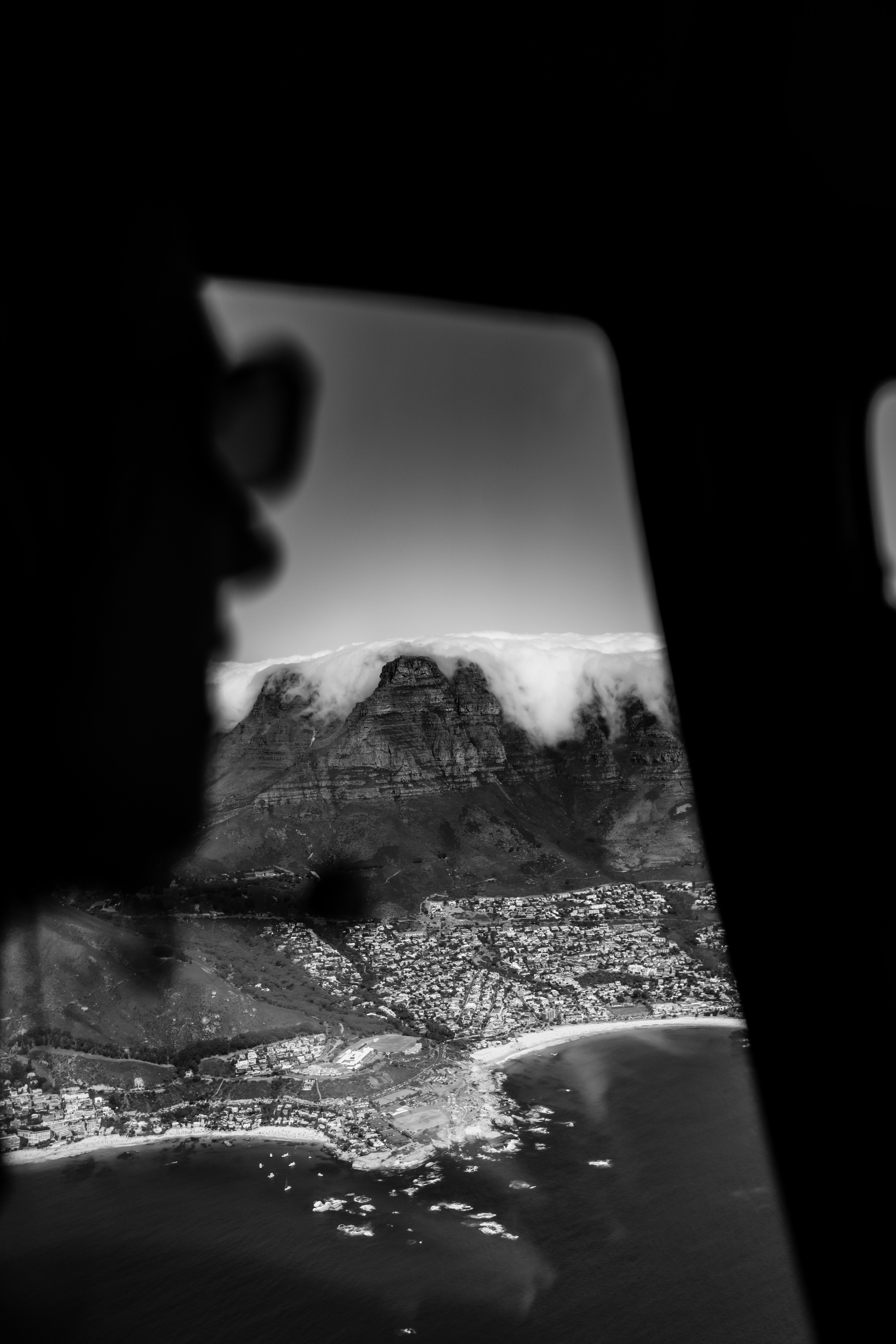 Aerial view of a city nestled below a cloud-covered mountain.
