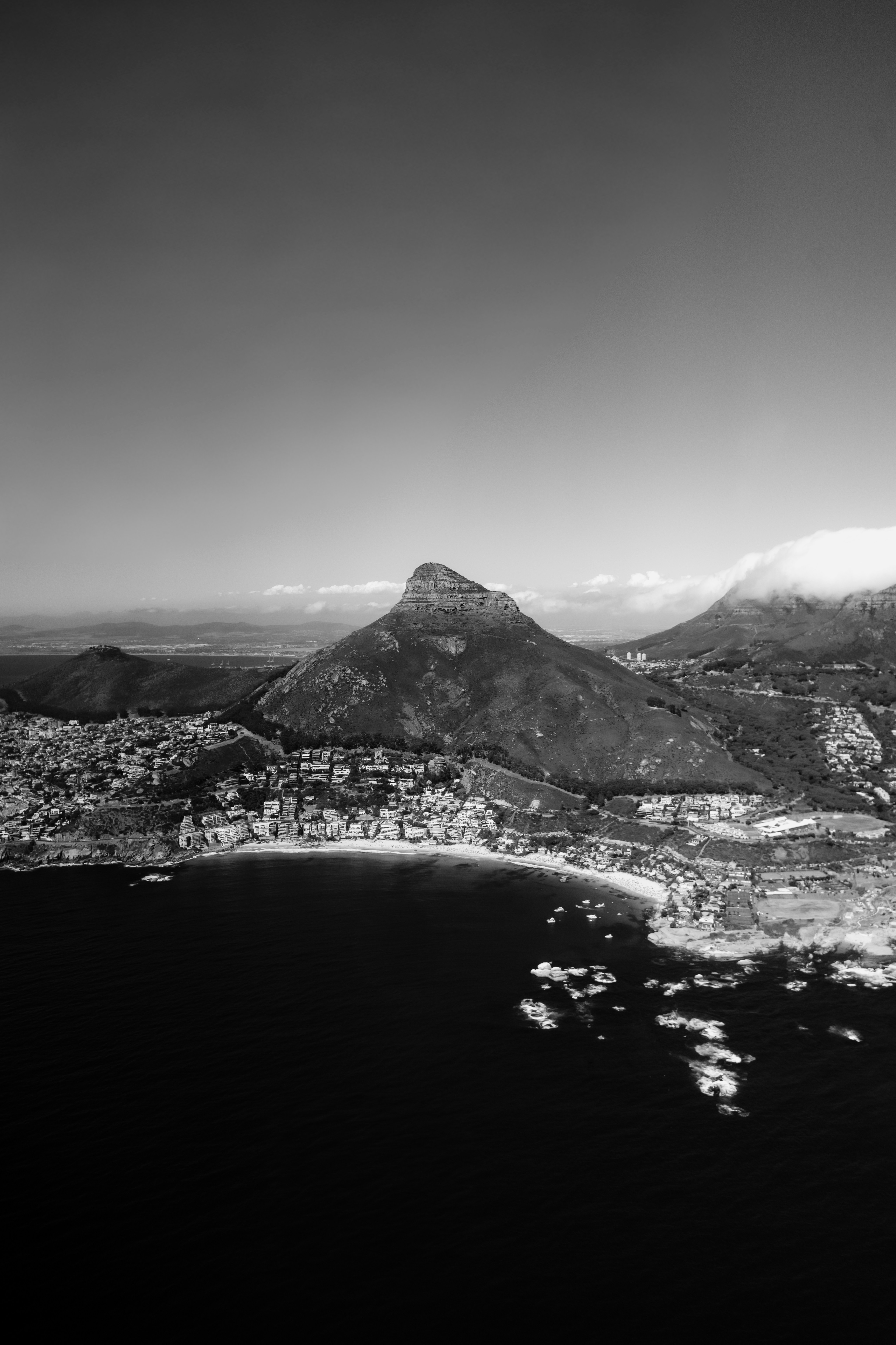 Vista aérea de una ciudad costera con una montaña prominente.