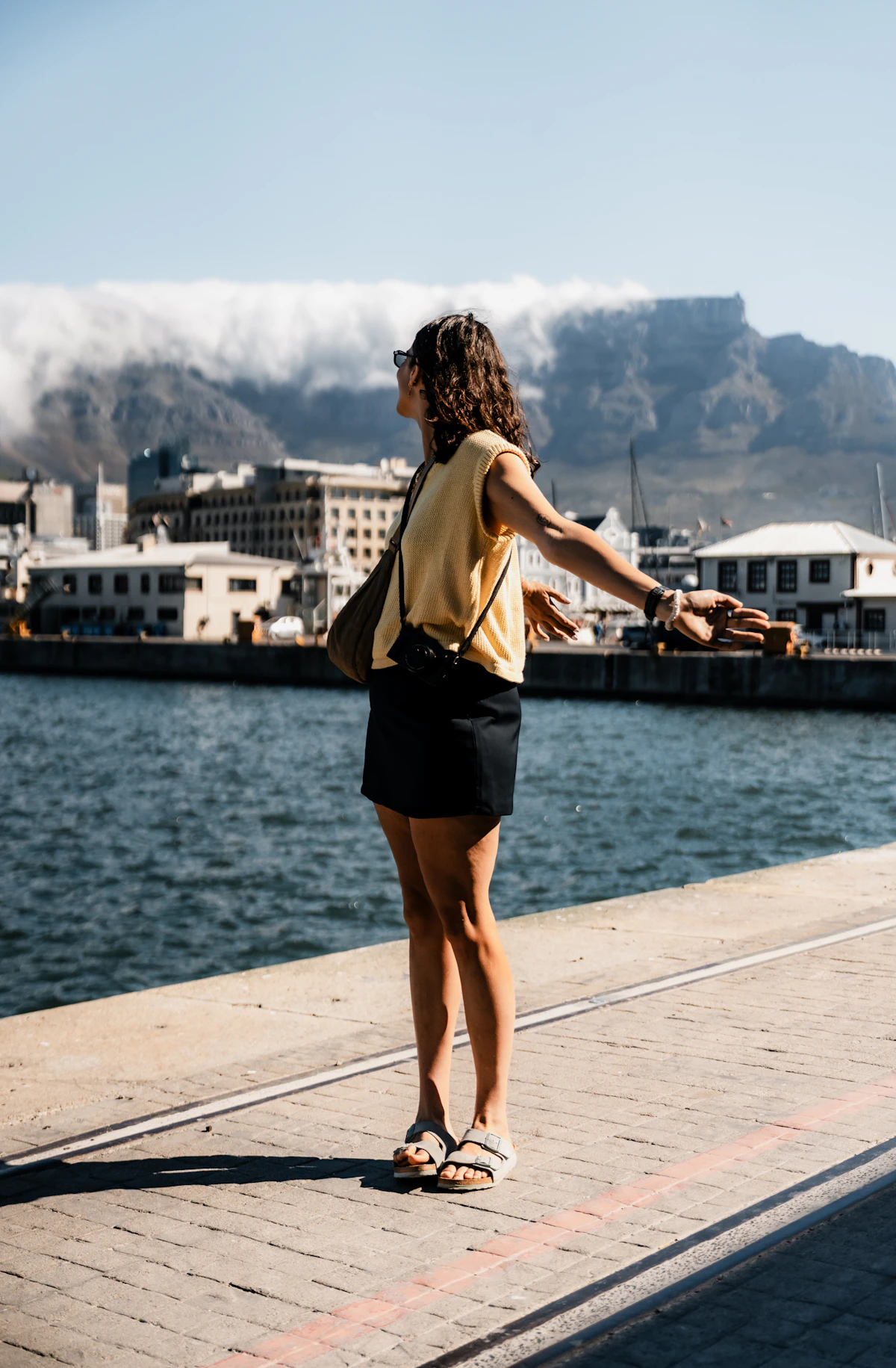 A woman standing with open arms beside the water, expressing freedom and possibility