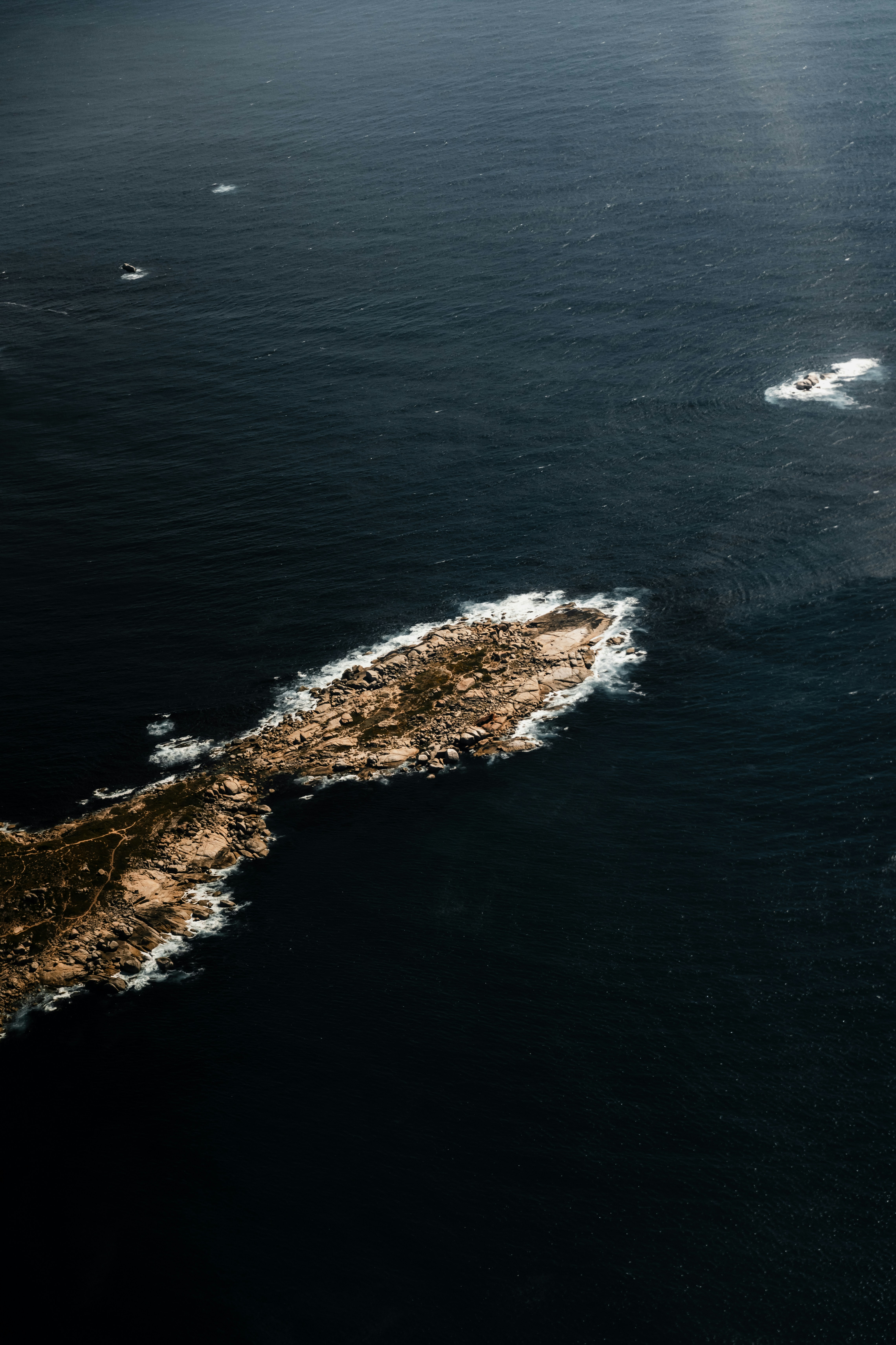 濃紺の海に浮かぶ岩礁の島の空撮
