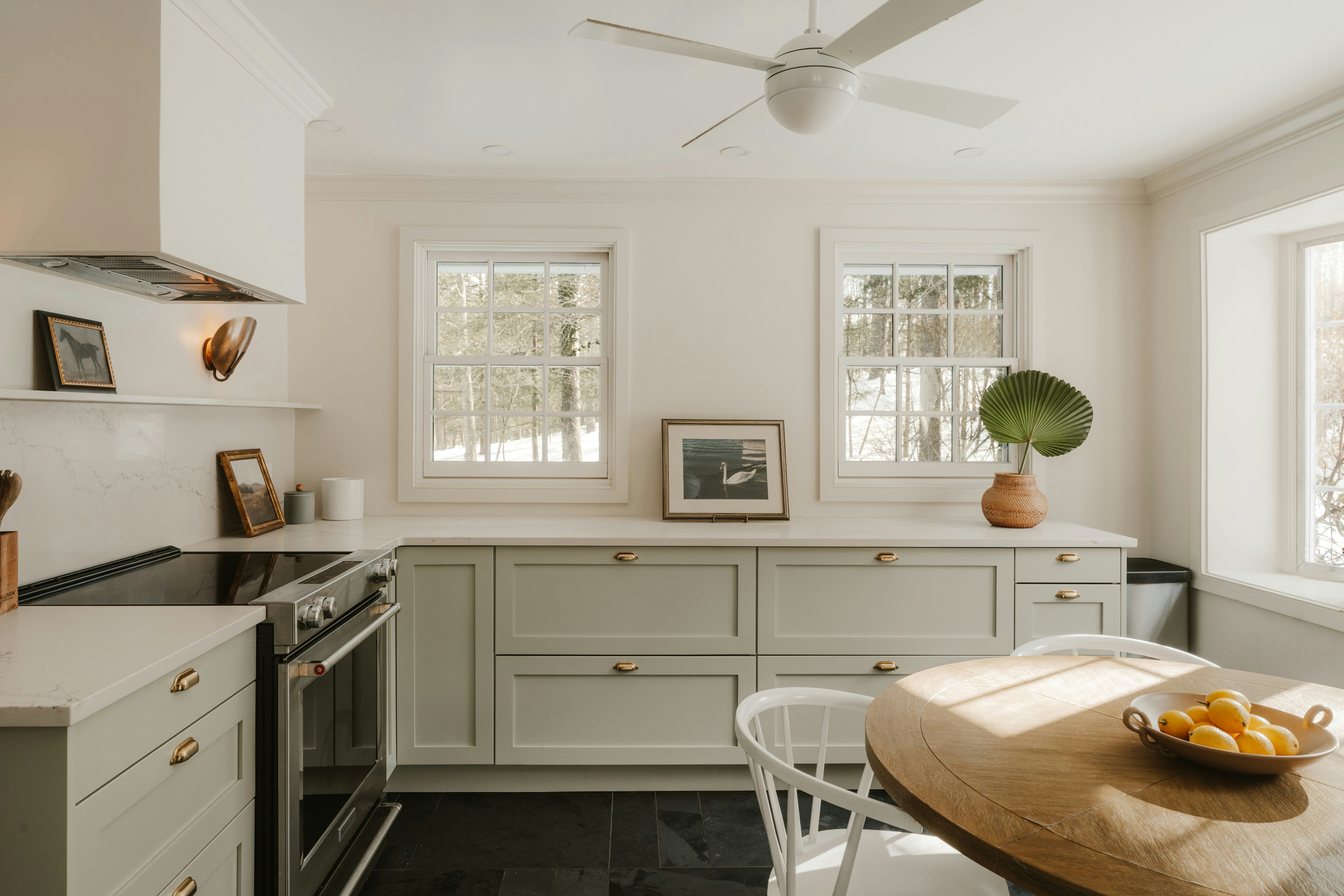 Bright kitchen with light green cabinets and wooden table.