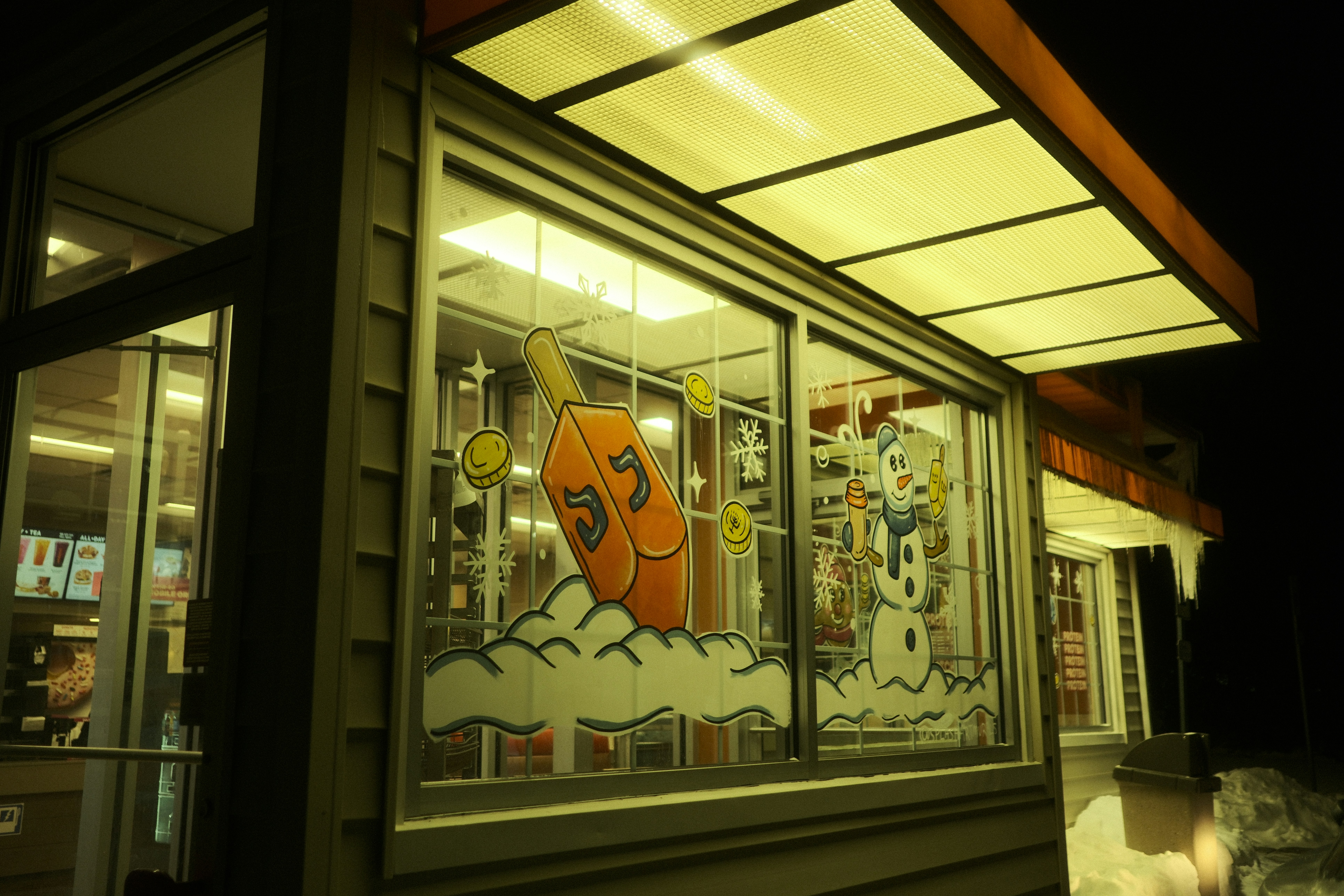 A building at night with illuminated windows displaying art.