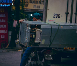 Man on motorcycle transports large appliance on truck