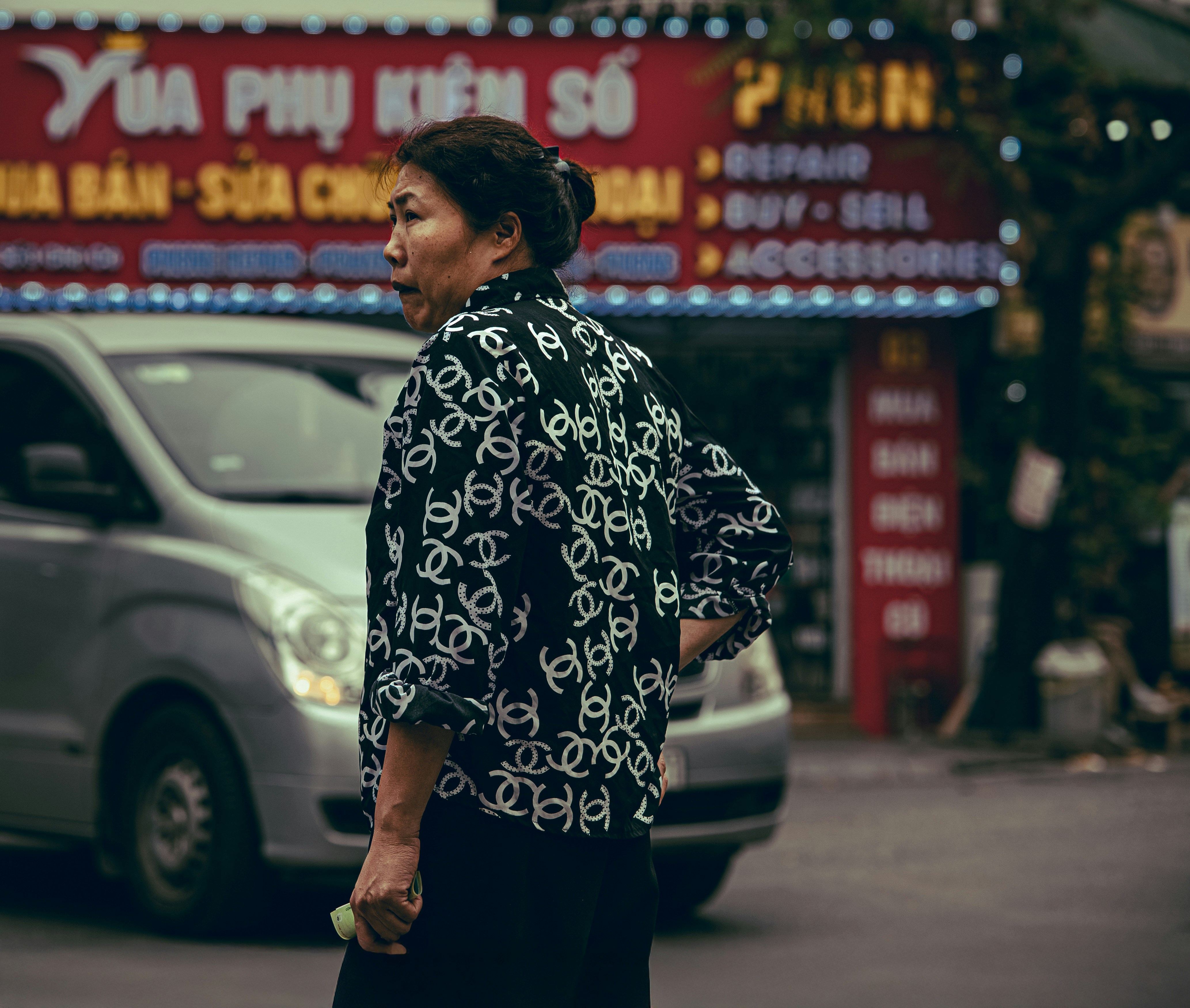 Woman in patterned shirt crosses street with car behind