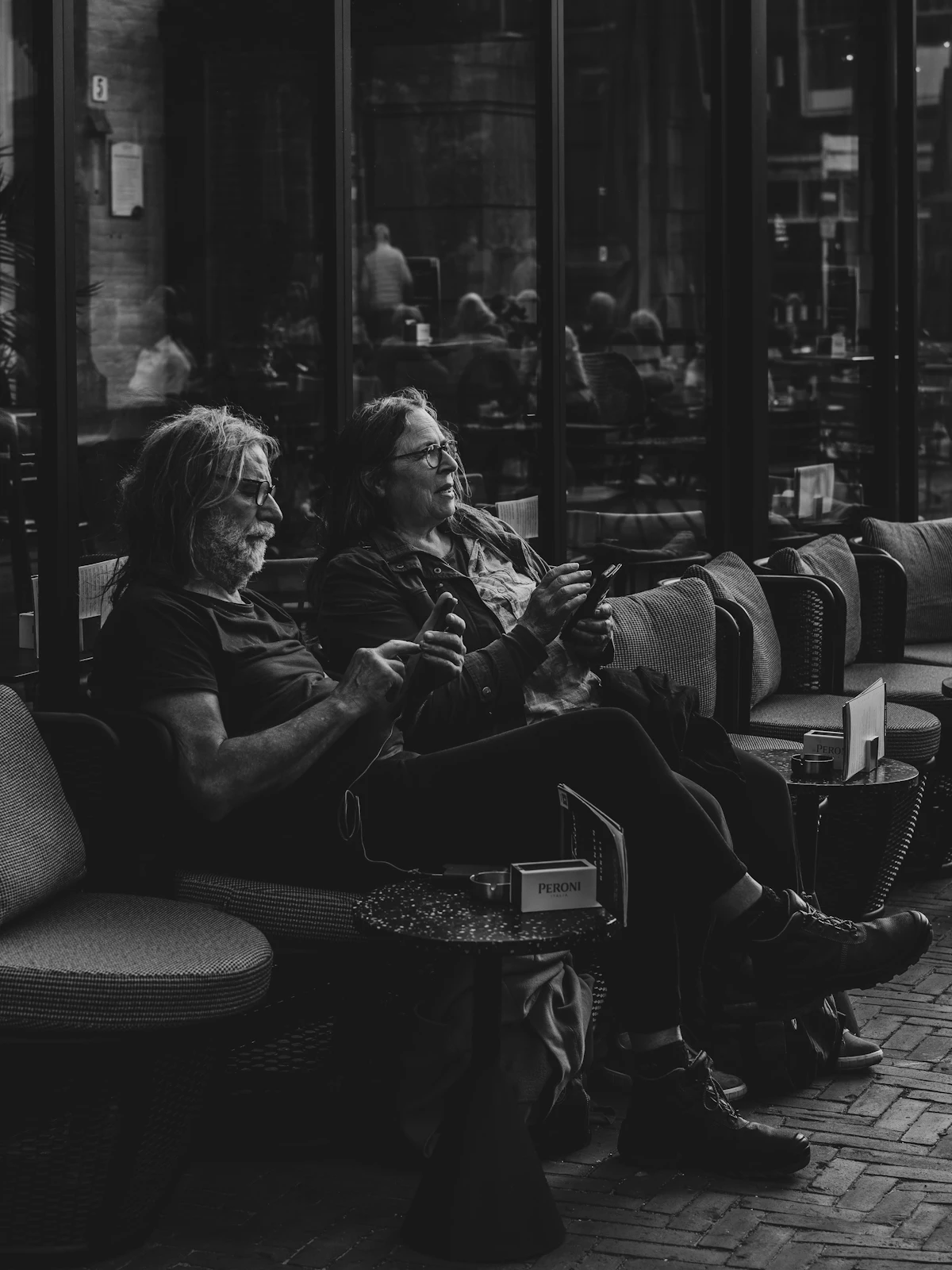 A couple sitting side by side on a sofa, each absorbed in their own phone instead of talking to each other.