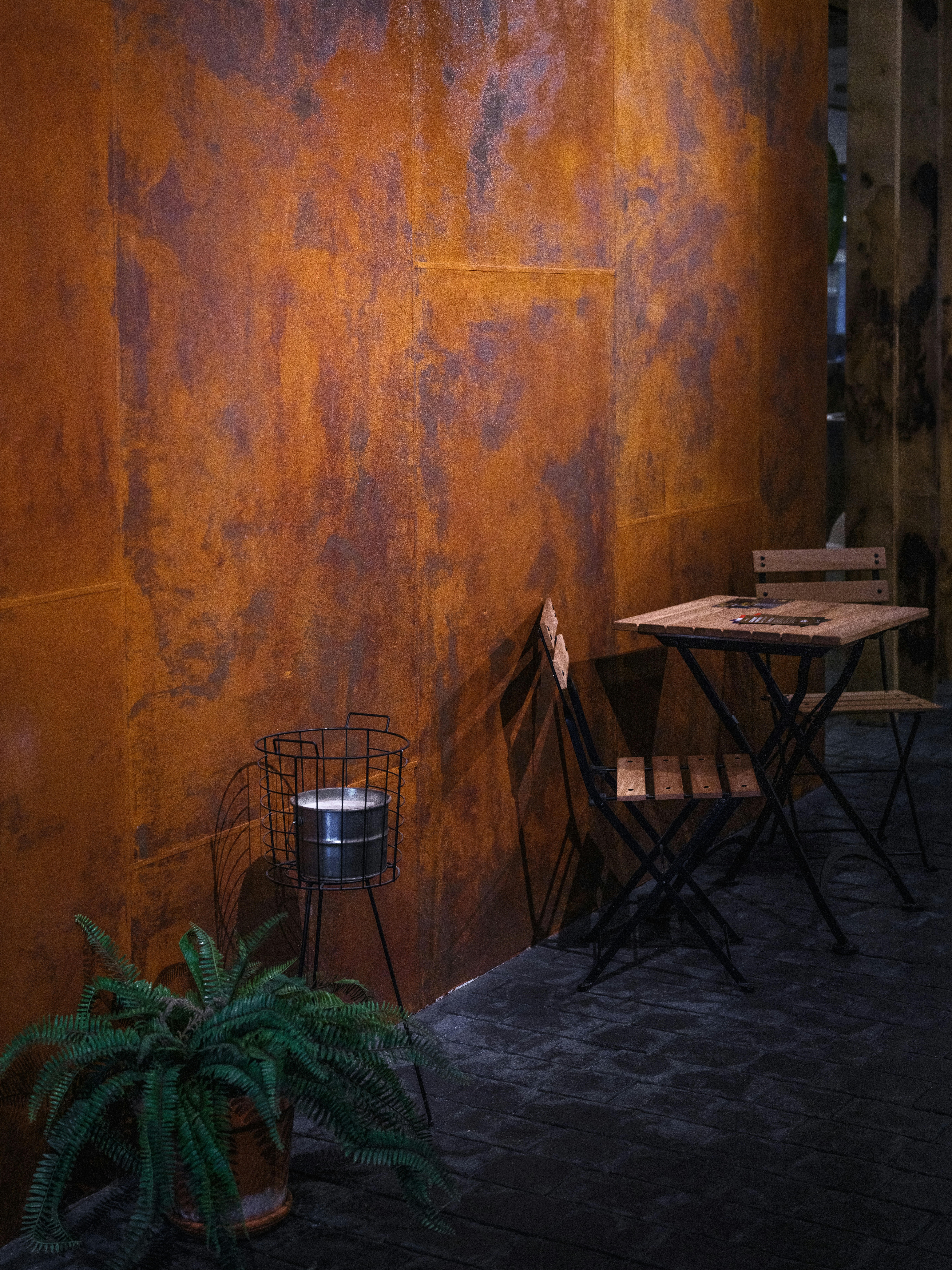 Metal wall with table and chairs in a plant