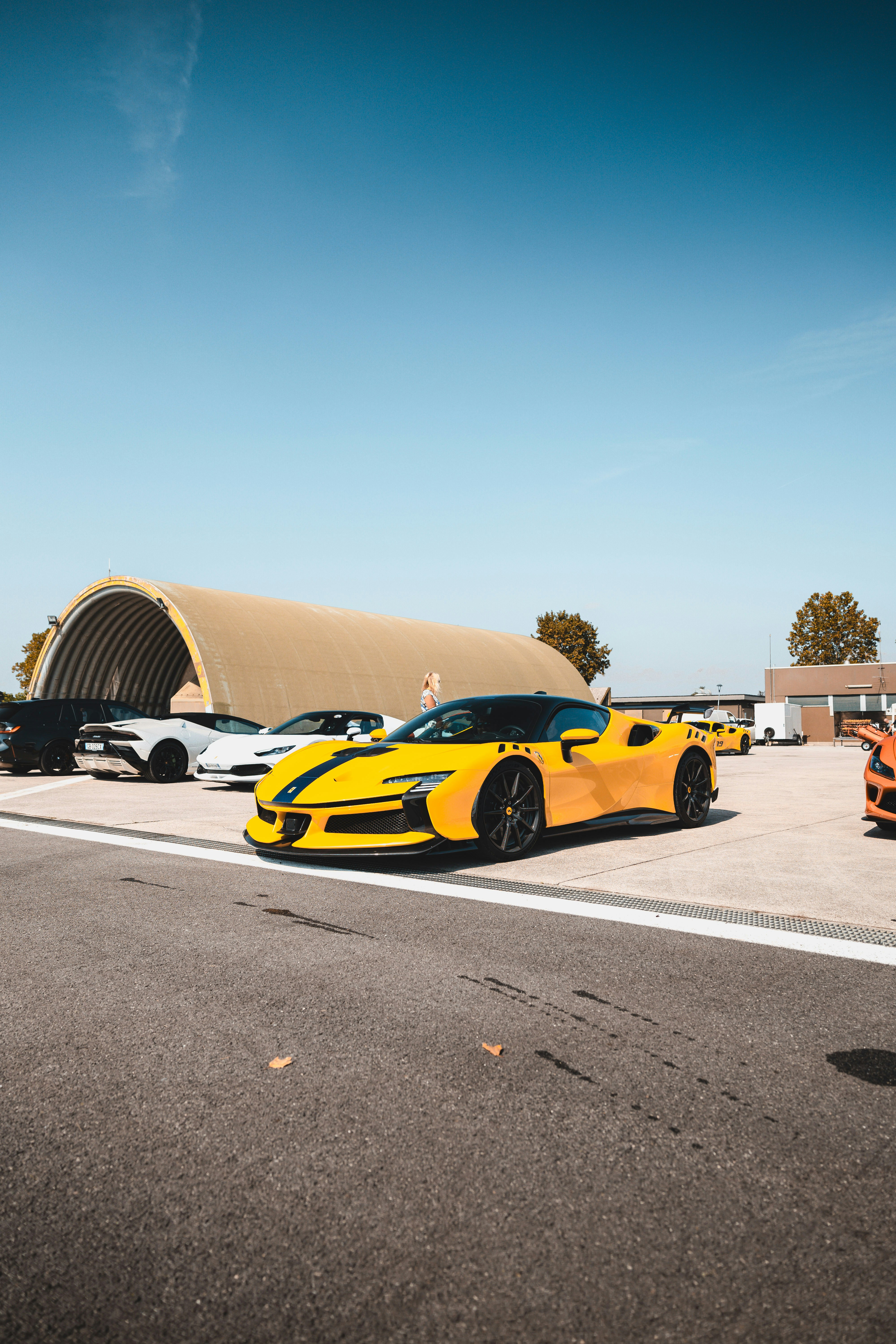 Mobil sport kuning diparkir di luar gedung dengan kendaraan lain.