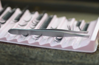 Una foto de una pinza especializada y diferentes extensiones de pestañas