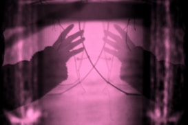Two hands reaching out in abstract pink light