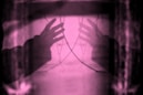 Two hands reaching out in abstract pink light