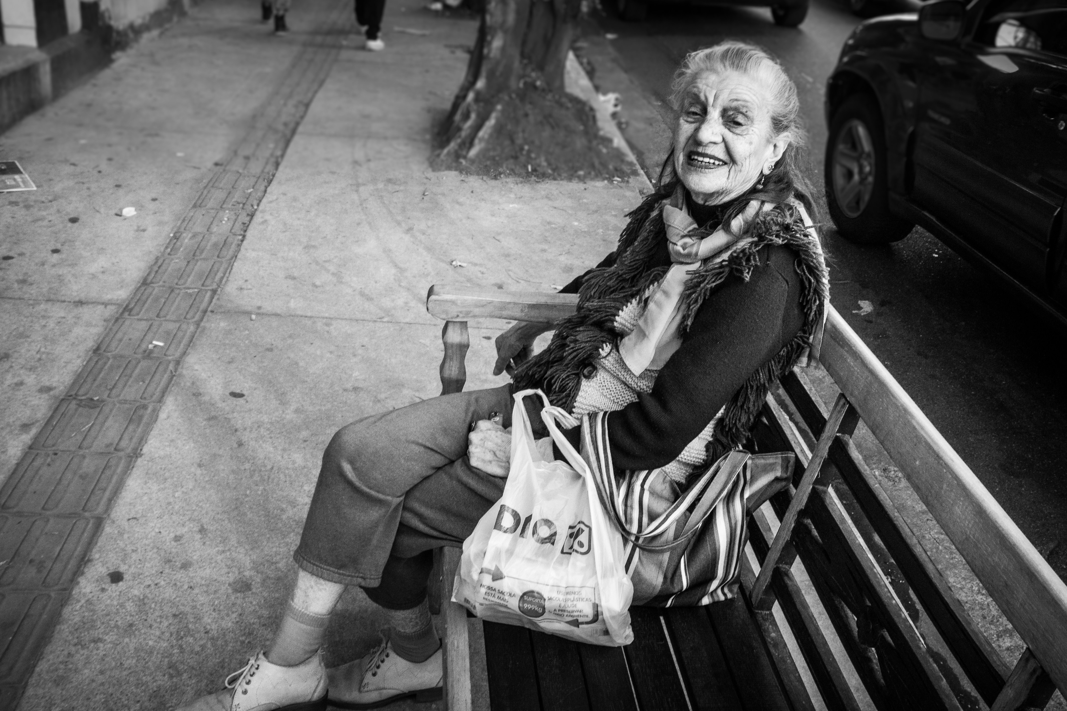 Anziana sorride seduta su una panchina del parco.