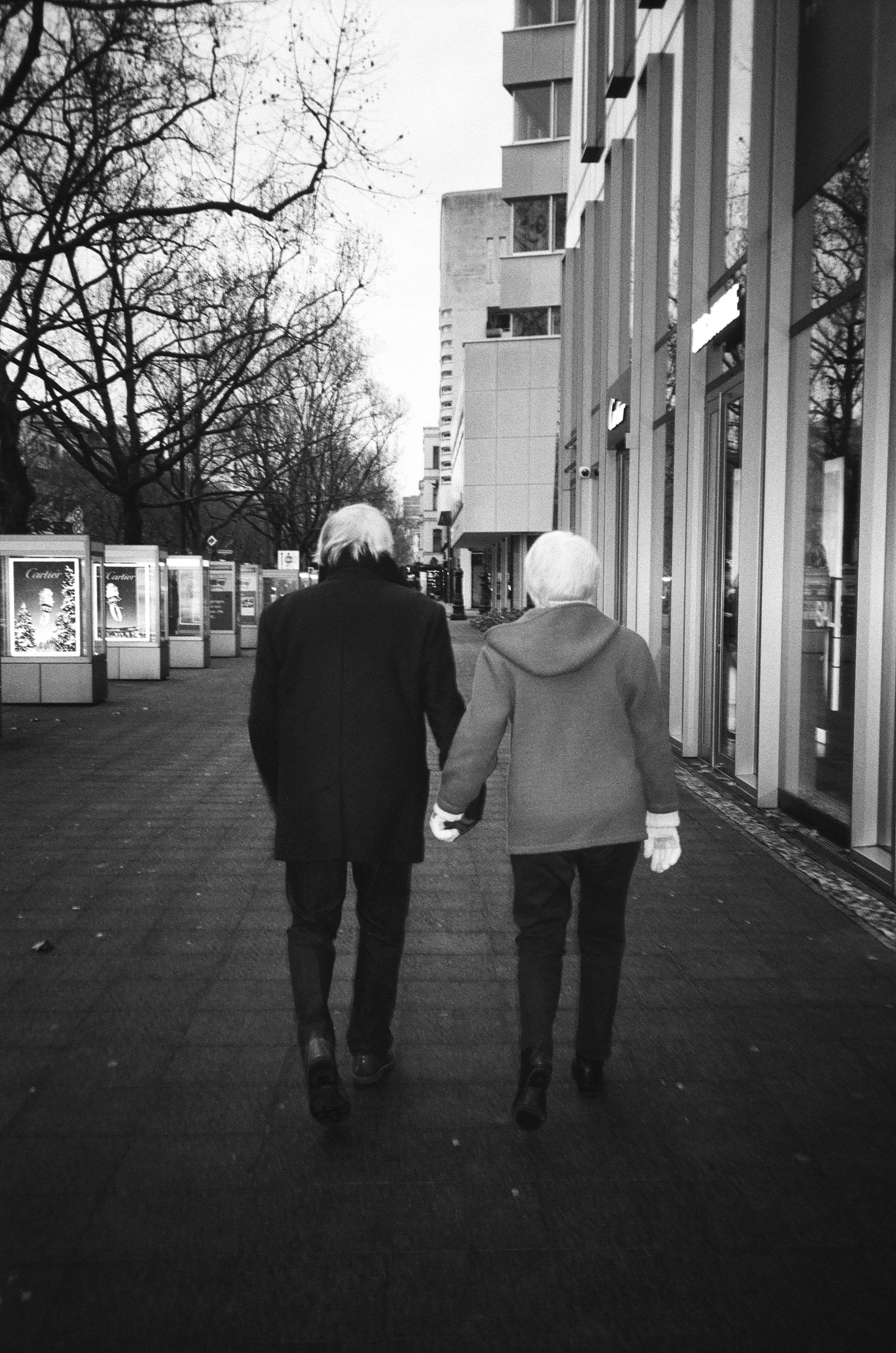 Elderly couple holding hands walking down street