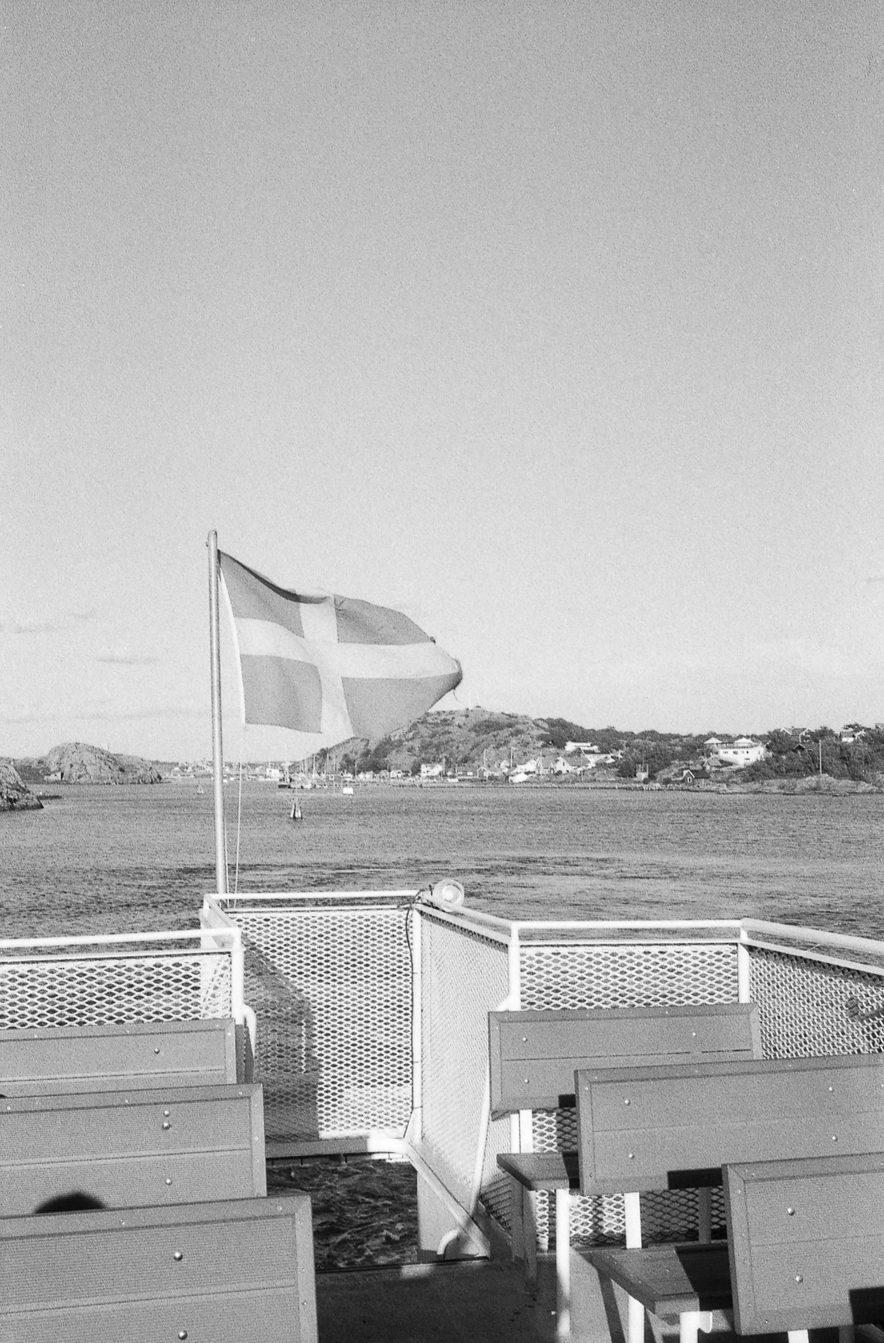 Danish flag waving on a boat with coastal town background