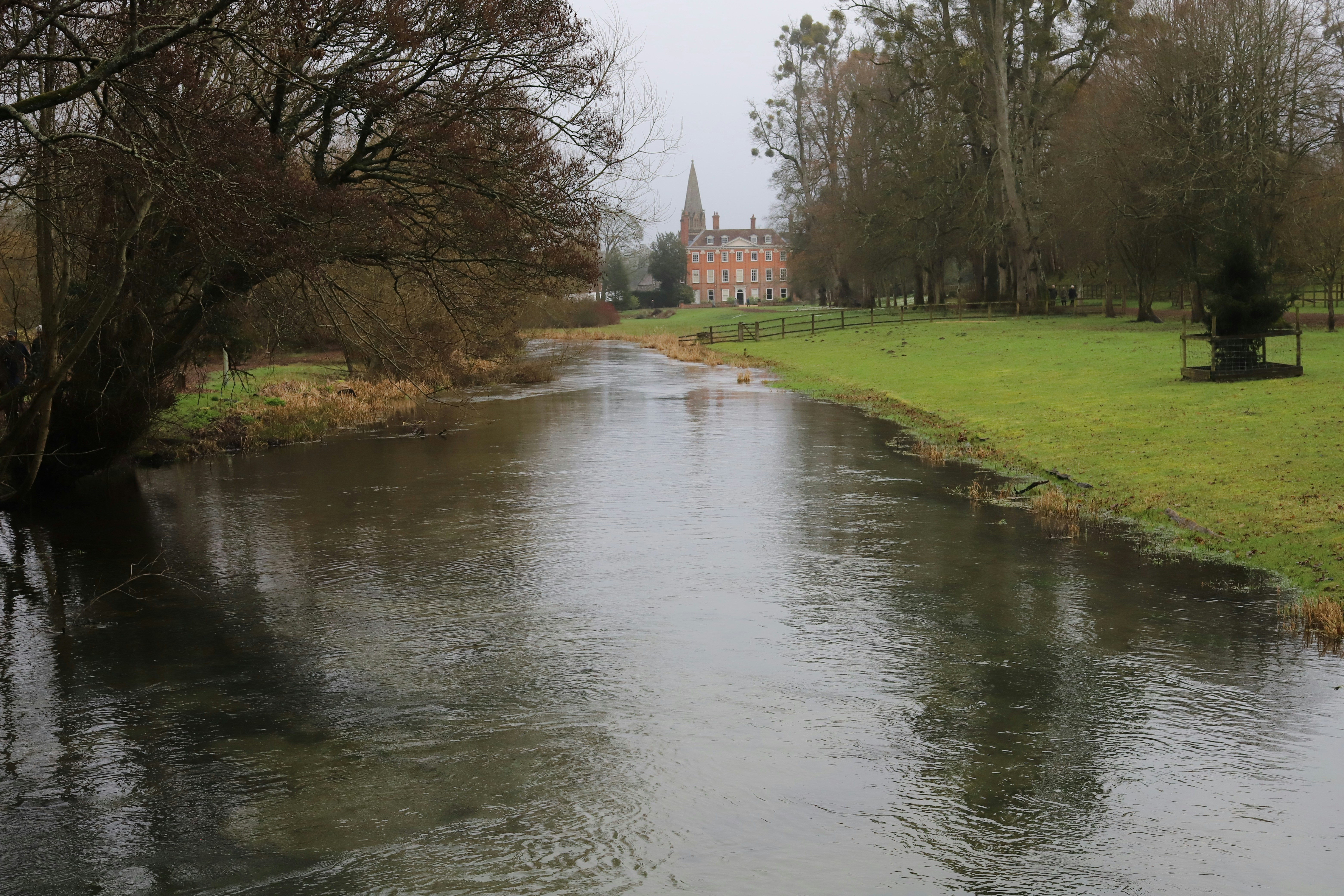 A brick building with a spire next to a river.