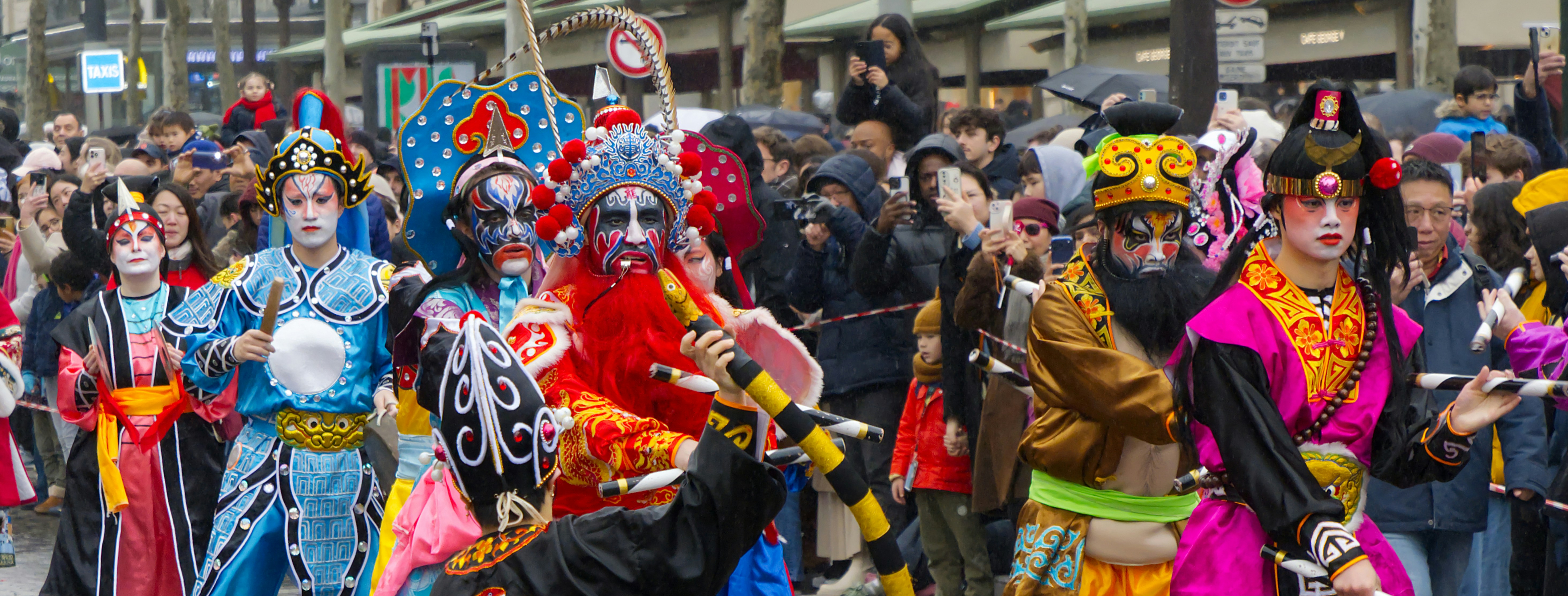 Performers in elaborate costumes and makeup during a parade.